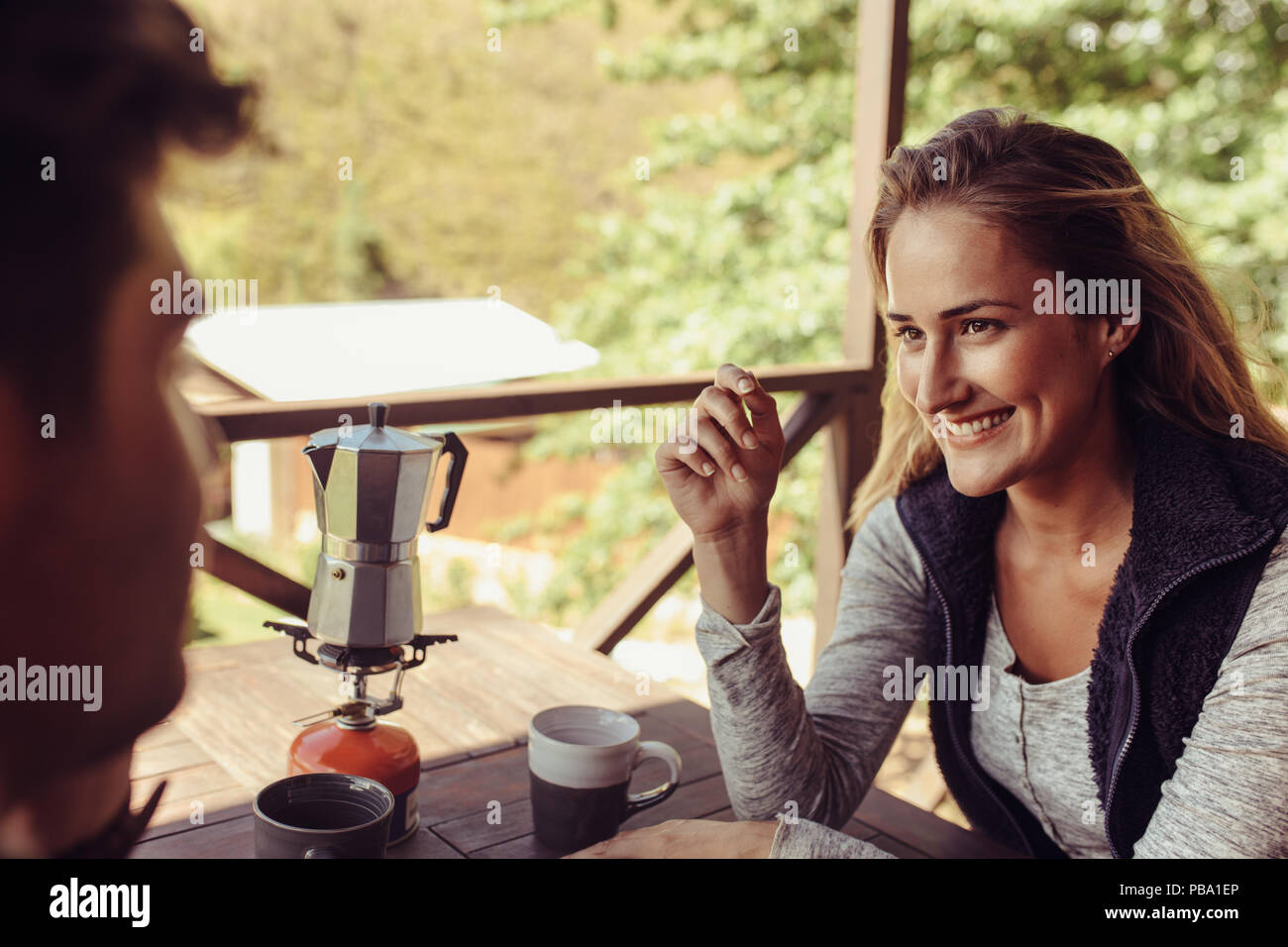 Schöne junge Frau außerhalb einer Kabine mit ihrem Freund sitzen und frühstücken. Paar im Urlaub Frühstück zusammen. Stockfoto