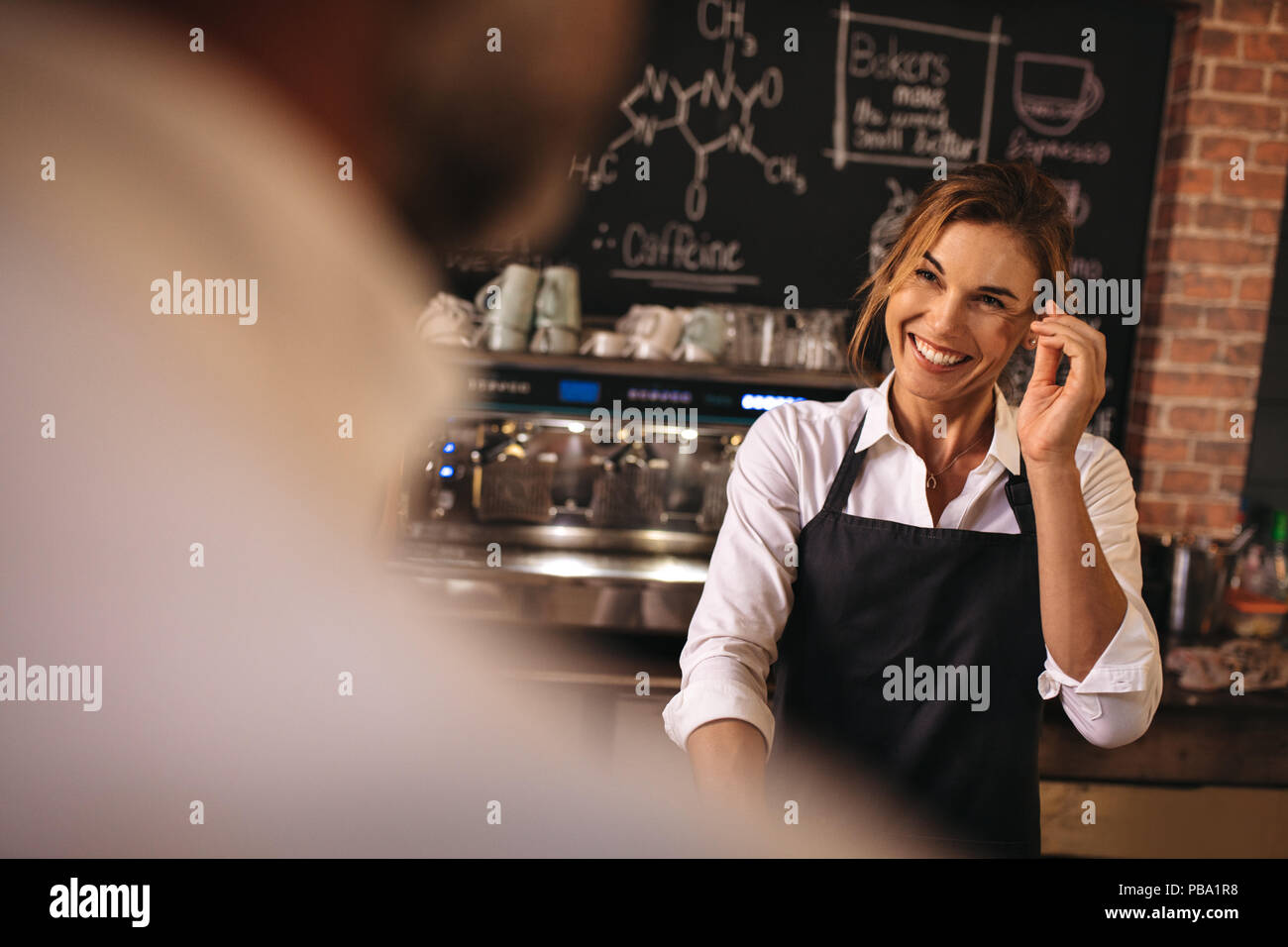 Lächelnd weibliche tragen Schürze in einer Bäckerei zu arbeiten. Frau Bäcker bei der Arbeit mit einem Mann vor. Stockfoto