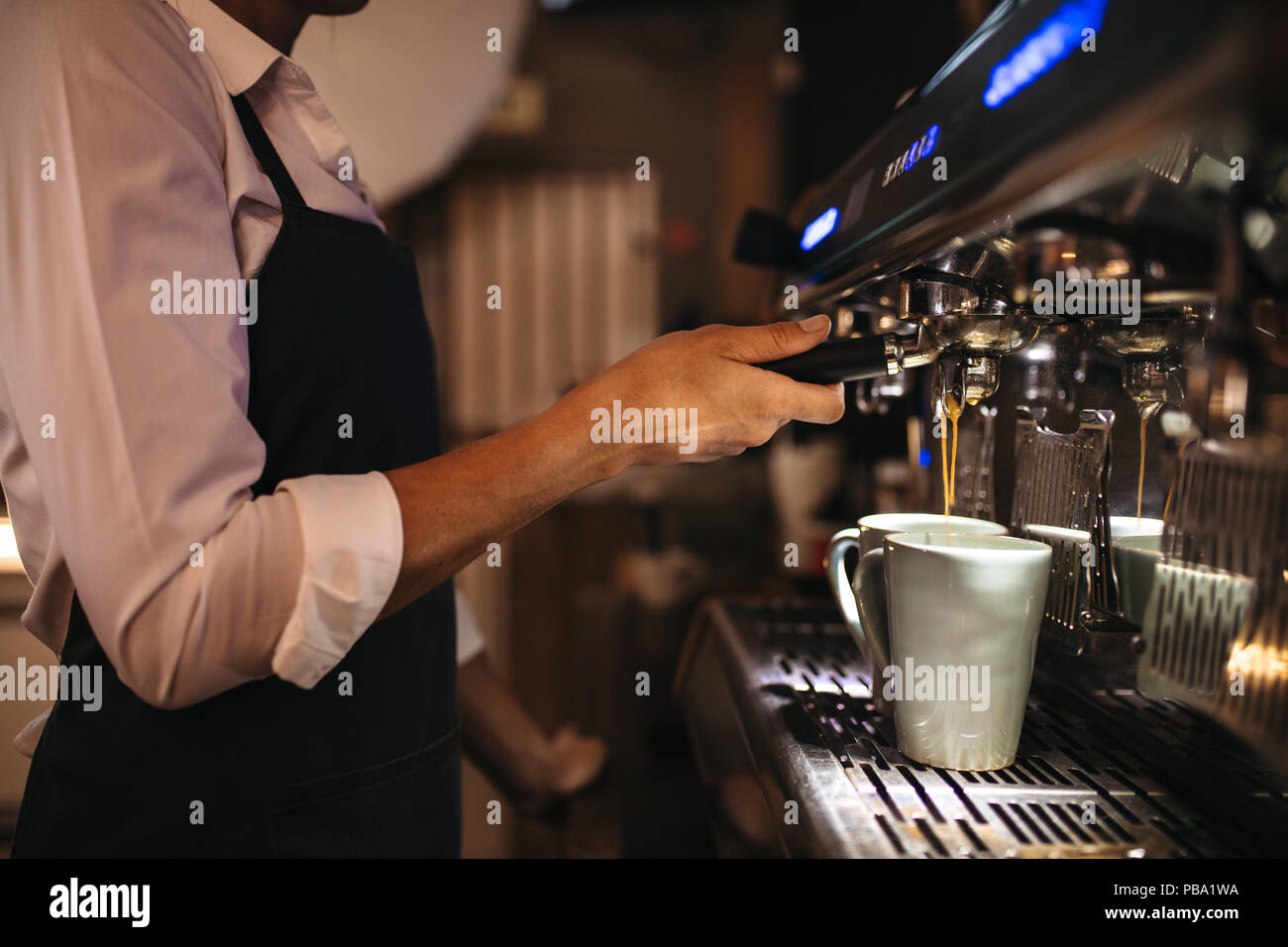 7/8 Schuß von Barista mit einer Kaffeemaschine, um eine Tasse Kaffee zu bereiten. Weibliche cafe Arbeiter einen Kaffee. Stockfoto