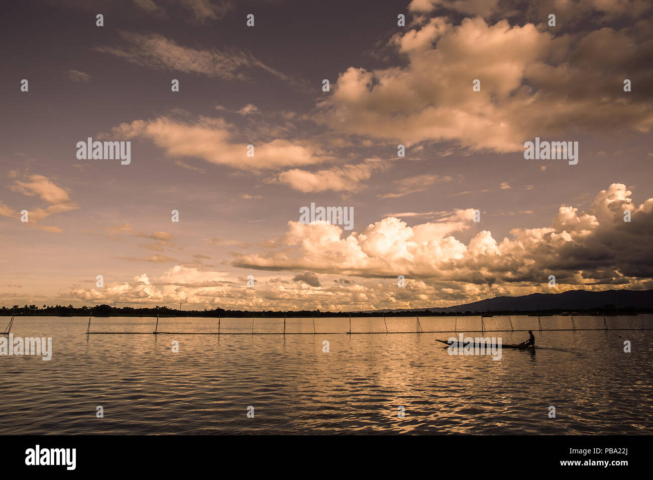 Ruhigen See Sonnenuntergang mit Silhouette Fischerboot warmen Ton Stockfoto