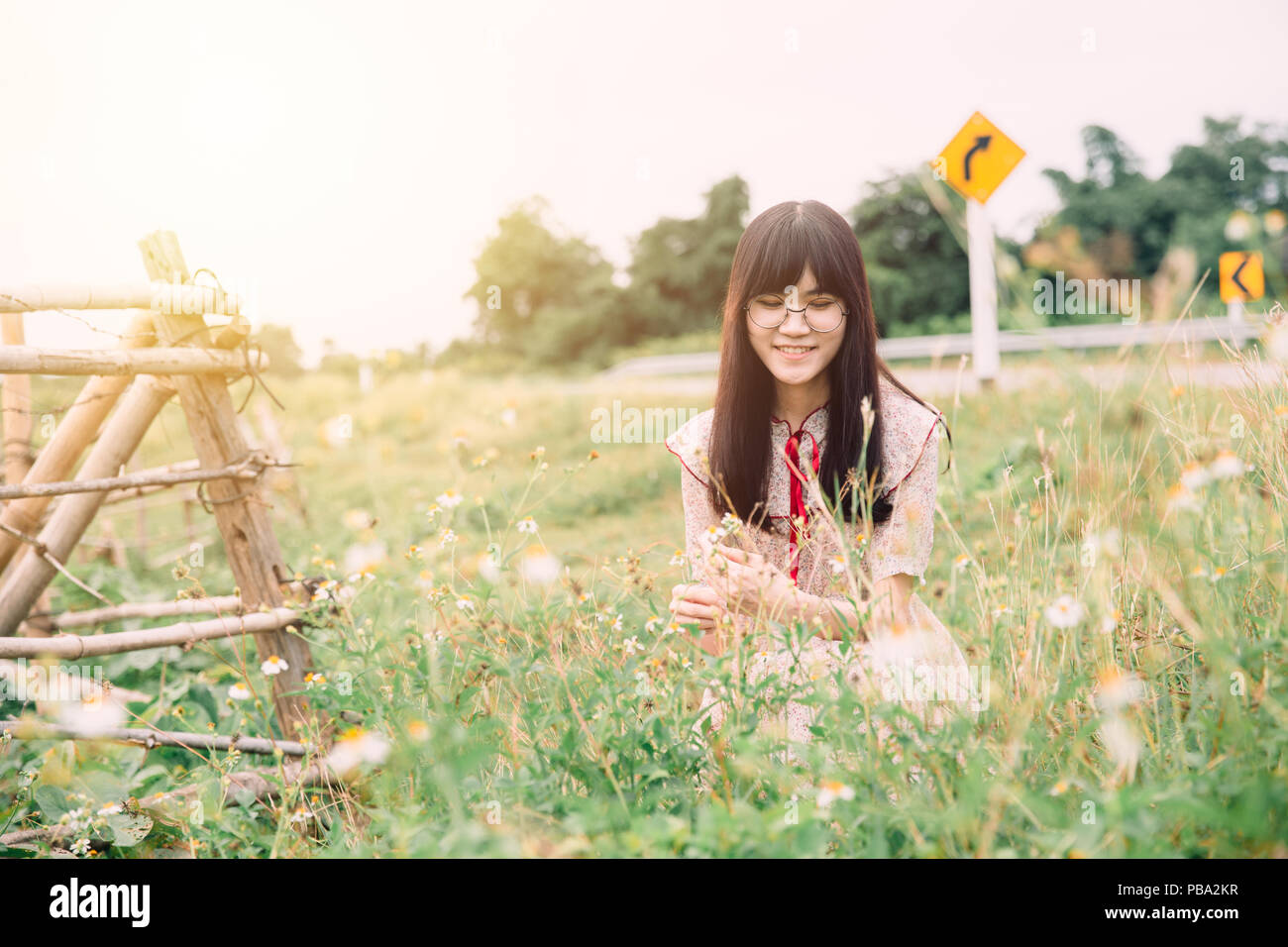 Süße asiatische Mädchen lächeln an der wiese gras Feld Blume am Straßenrand Stockfoto