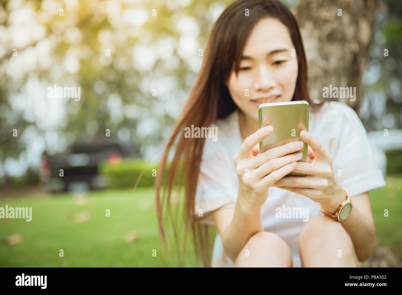 Asian teen genießen Sie ihr Smartphone Konnektivität lifestyle Outdoor im Green Park. Stockfoto
