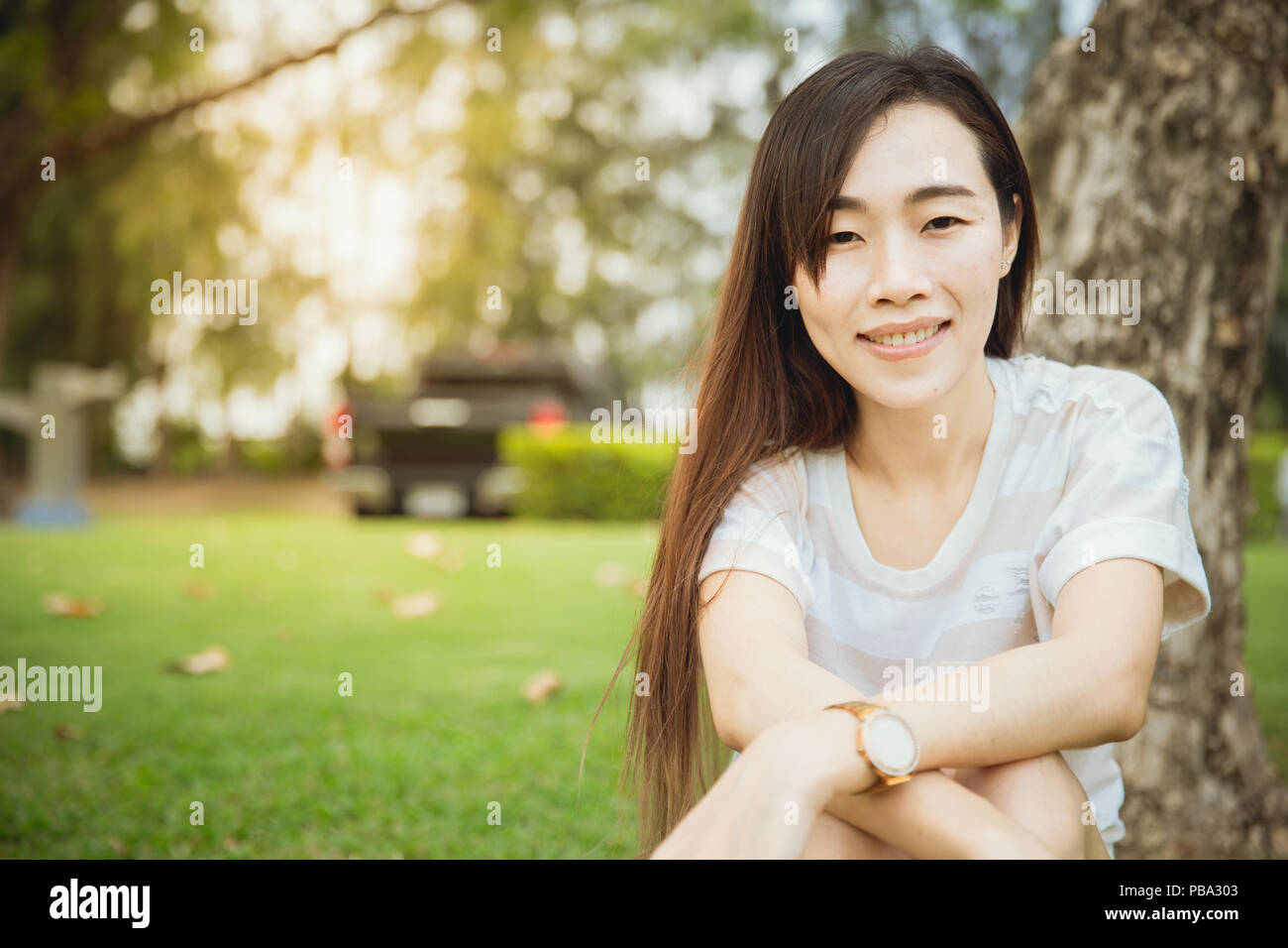 Closeup Asian teen Chinesische Rasse single Augenlid lange Haare sitzen Lächeln mit Grübchen Wange im Park Stockfoto