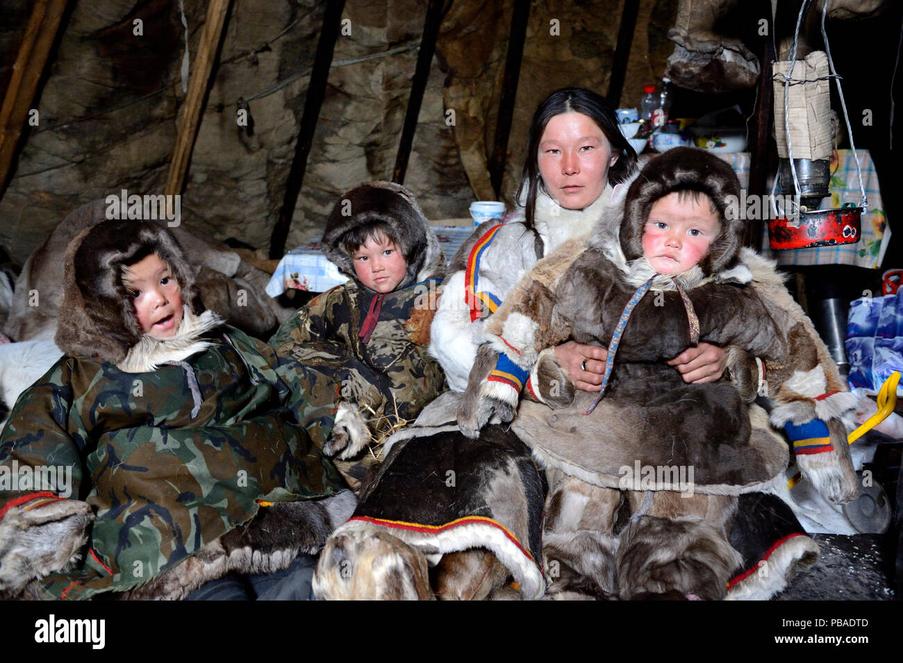 Nenet herder im Zelt mit Tochter und Söhne, tragen Mäntel mit Rentier Haut und Fell. Yar-Sale Bezirk. Yamal im Nordwesten von Sibirien, Russland. April 2016. Stockfoto