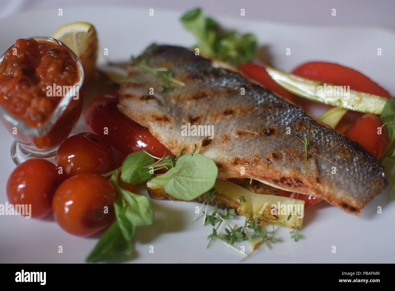 Russische Küche - Gegrillter Fisch mit Gemüse und Tomaten Stockfoto