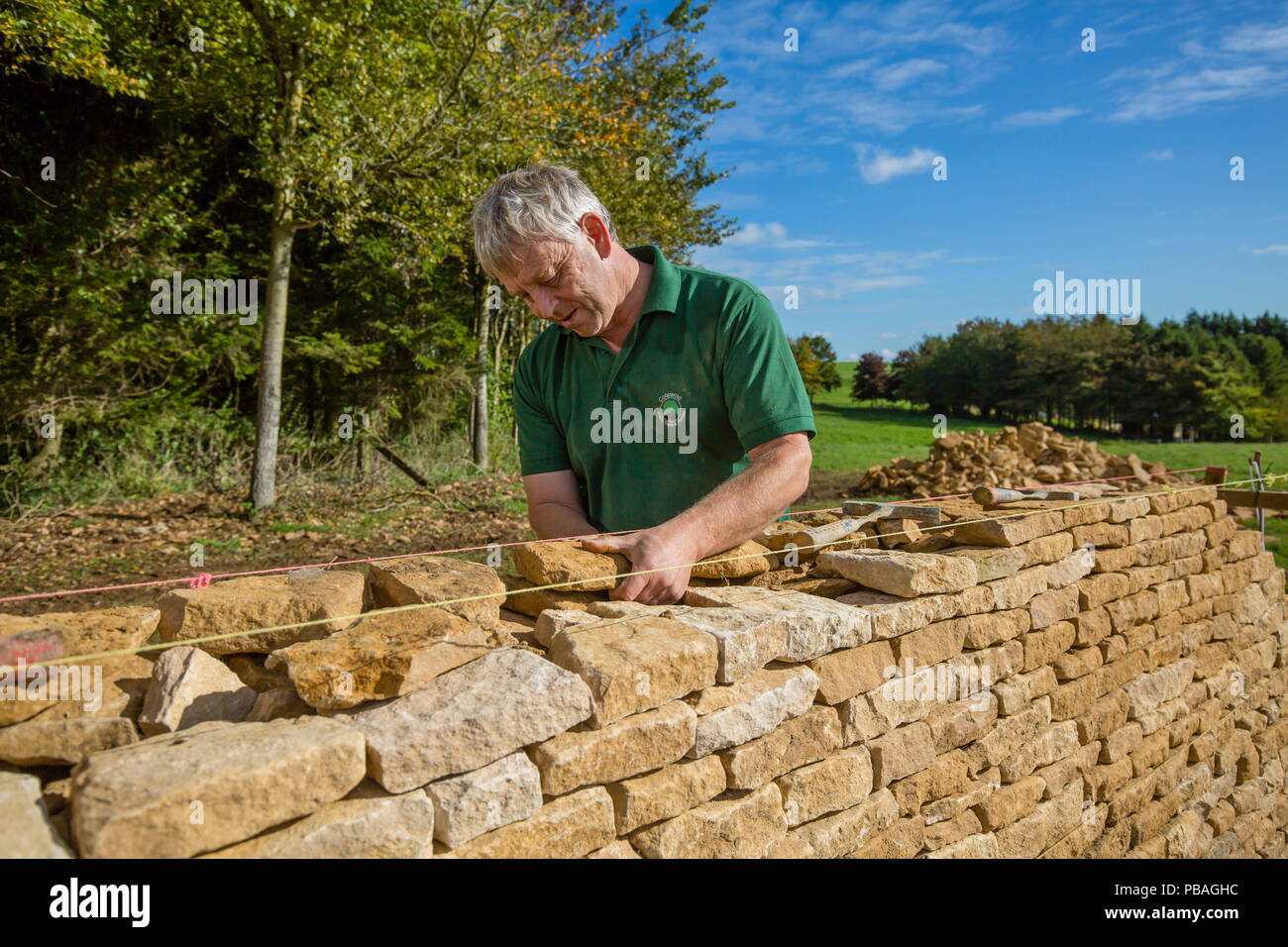 Traditionelle Trockenmauern Waller arbeiten mit Cotswolds Kalkstein eine Mauer, Guiting Macht, Gloucestershire, Vereinigtes Königreich. Oktober 2015. Stockfoto