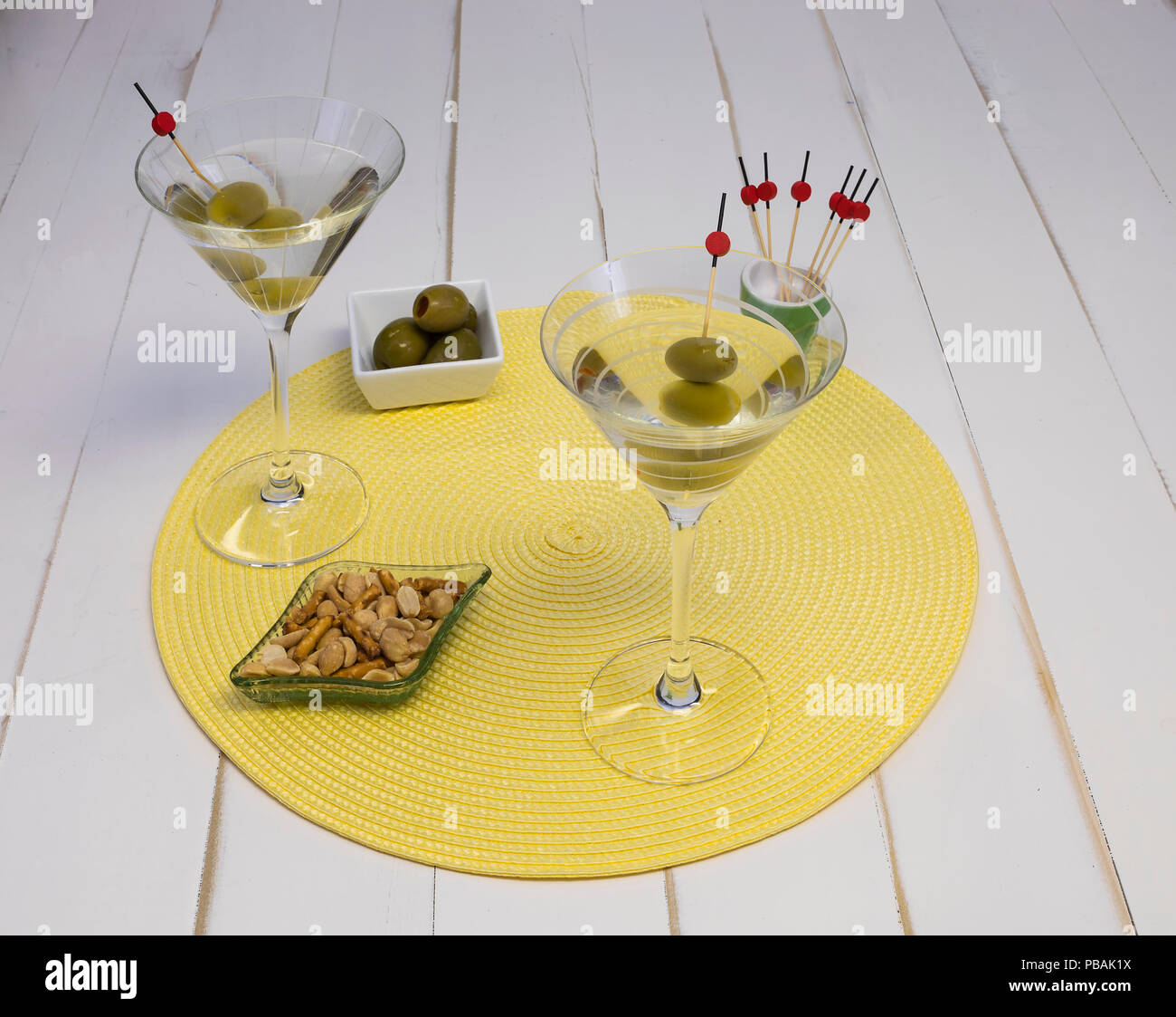 Zwei Wodka Martini in Gläsern mit Oliven und Snacks auf ein Tischset, Vorderansicht. Stockfoto