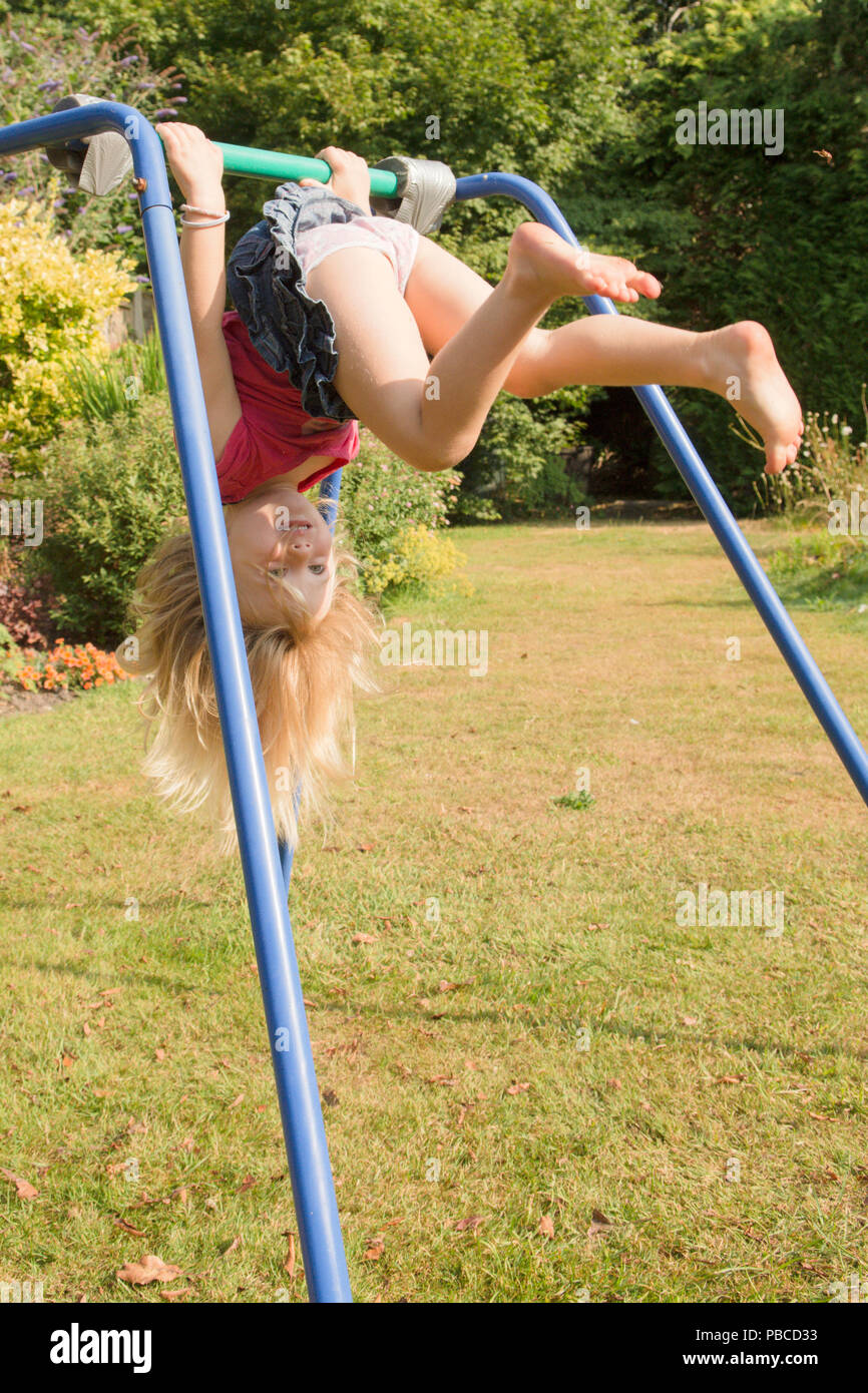 Drei Jahre altes Mädchen turnen Akrobatik auf Apparate, die in der Garten für Spiel, Großbritannien. Stockfoto