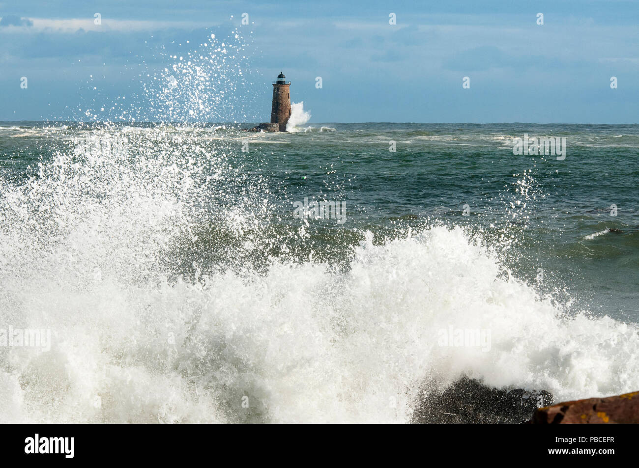 Einzigartige Flut verursacht große Wellen um die Ufer und um einen Stein Leuchtturm in Maine zu brechen. Stockfoto
