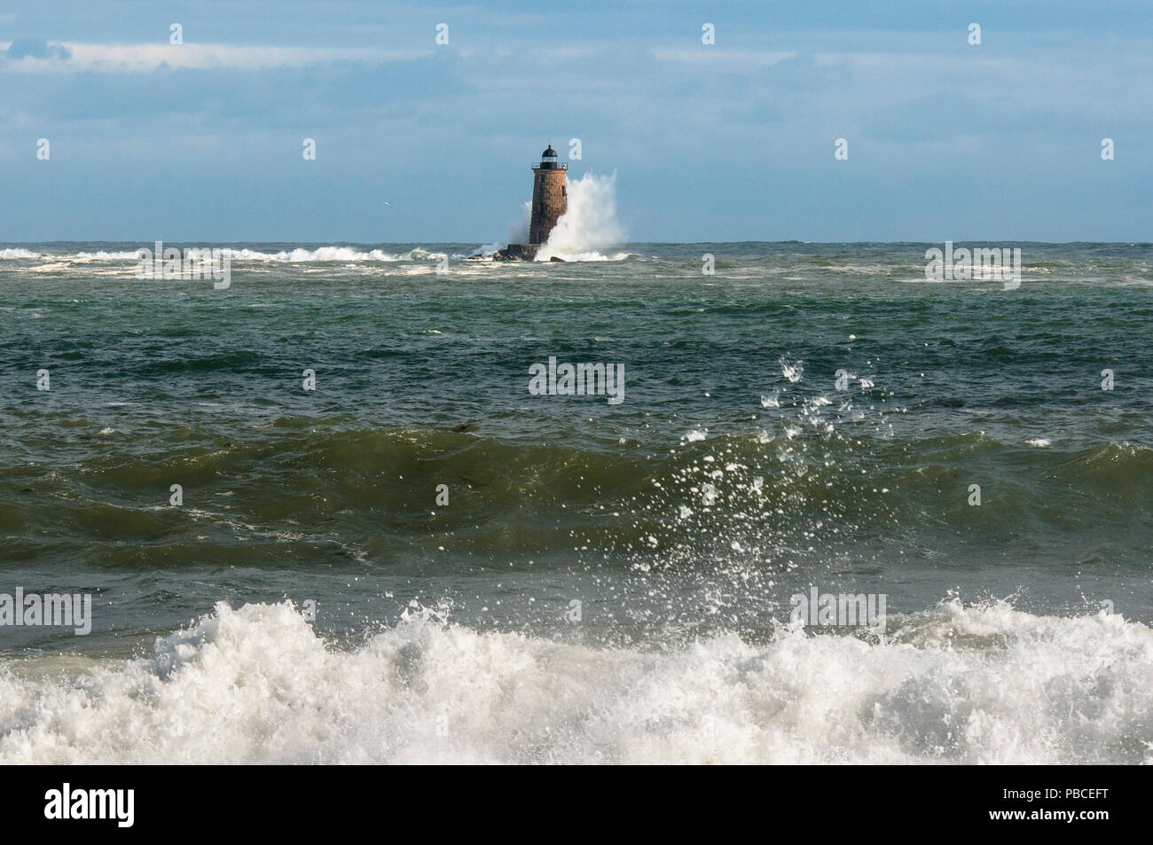 Einzigartige Flut verursacht riesige Wellen entlang der Küste und um einen Stein Leuchtturm in der Ferne in Maine zu brechen. Stockfoto