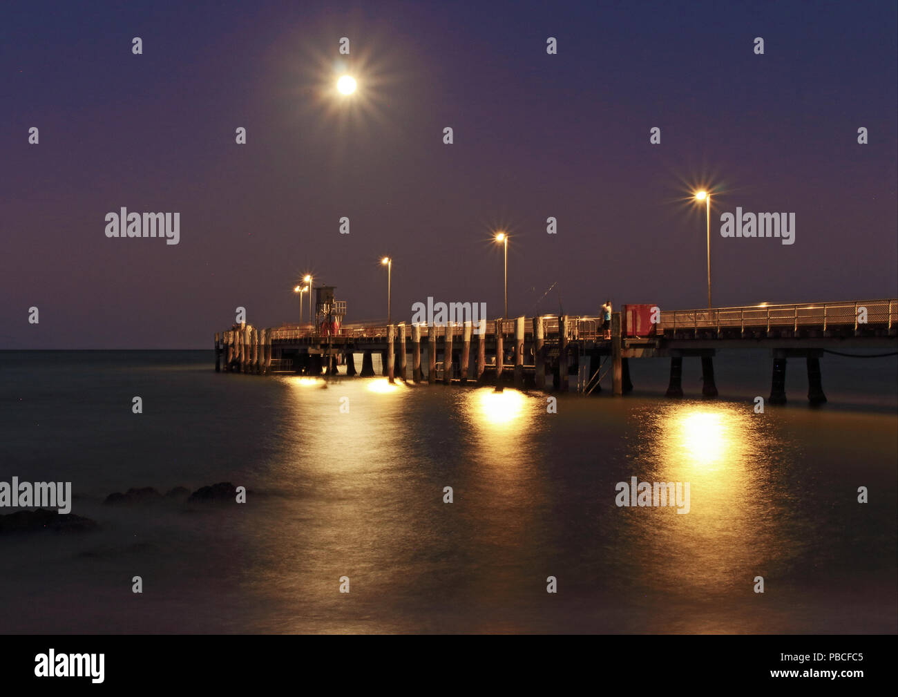 Palm Cove Jetty als Abend wird Nacht LE der Vollmond über den Pier gesetzt und das Hinzufügen Lichteffekte Stockfoto
