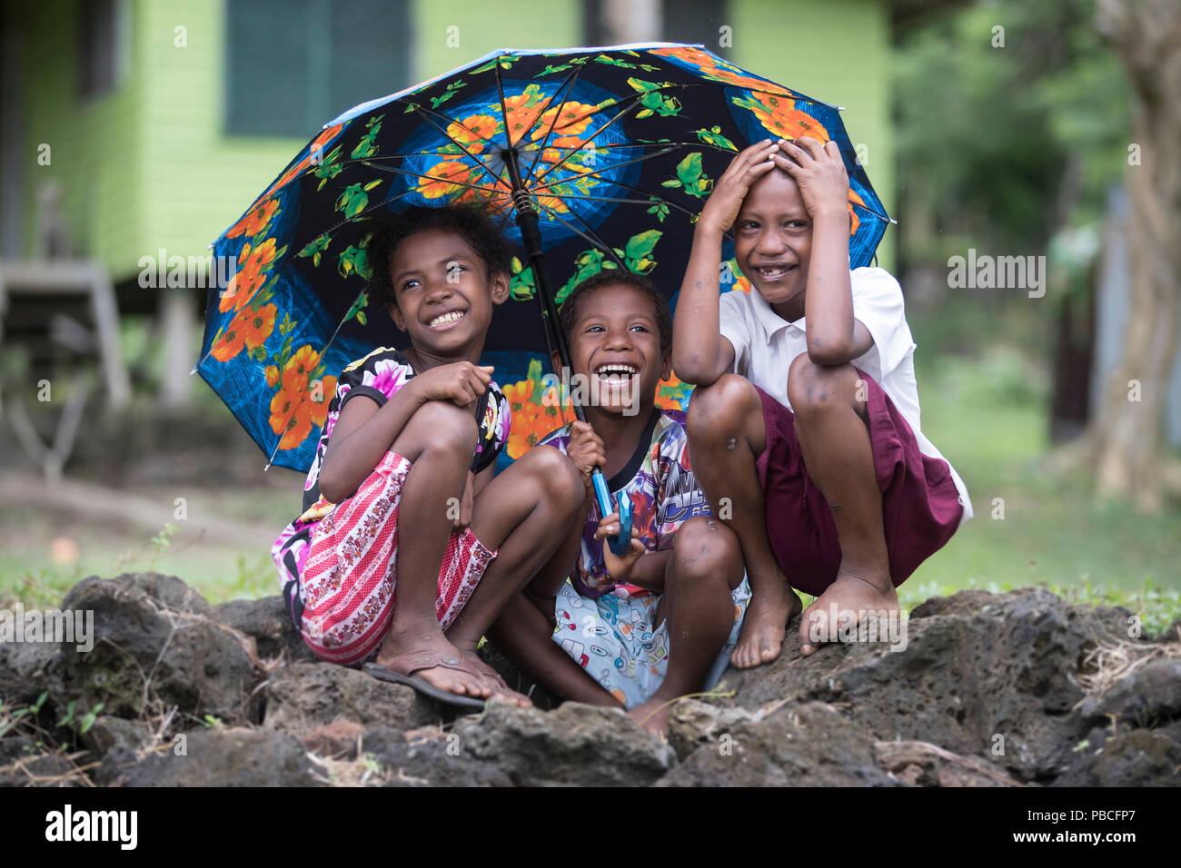 Drei Kinder sitzen unter einem Dach zusammen lachen - Papua-Neuguinea Stockfoto