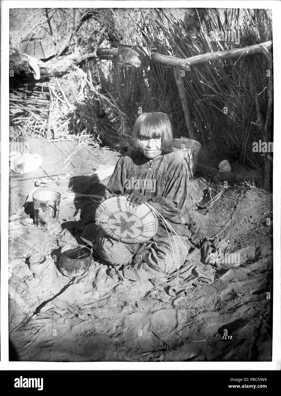 Englisch: Porträt eines Apache indische Frau Korbmacher, Ca. 1900  fotografische Porträt eines Apache indische Frau Korbmacher, ca. 1900. Sie  sitzt auf einem Tuch auf dem Boden mit einer teilweise bearbeiteten Korb