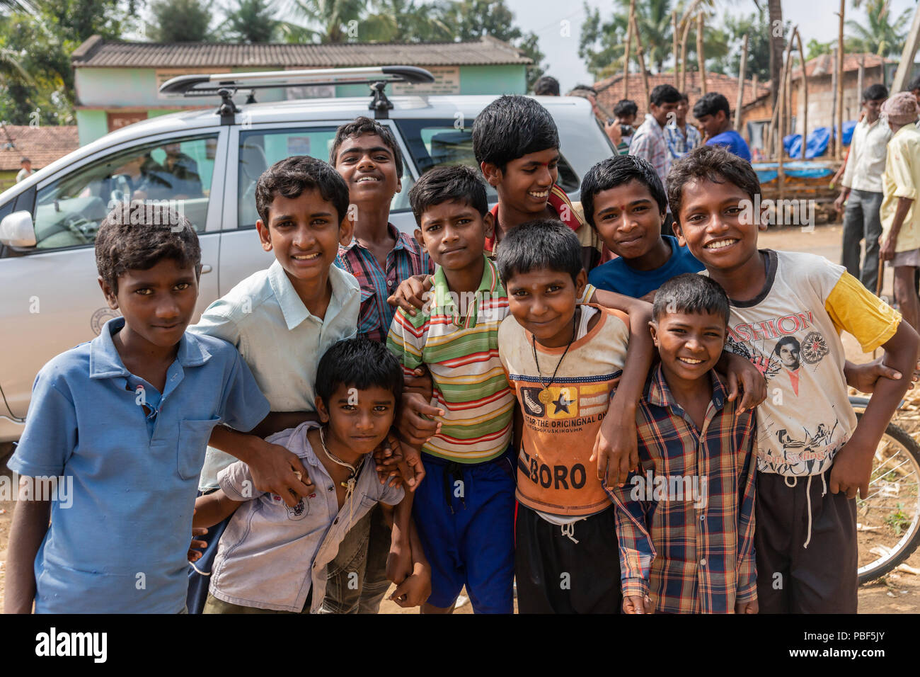 Belathur, Karnataka, Indien - 1. November 2013: eine Gruppe von Jungen in bunten Shirts entlang der Straße schauen und lächeln in die Kamera. Stockfoto