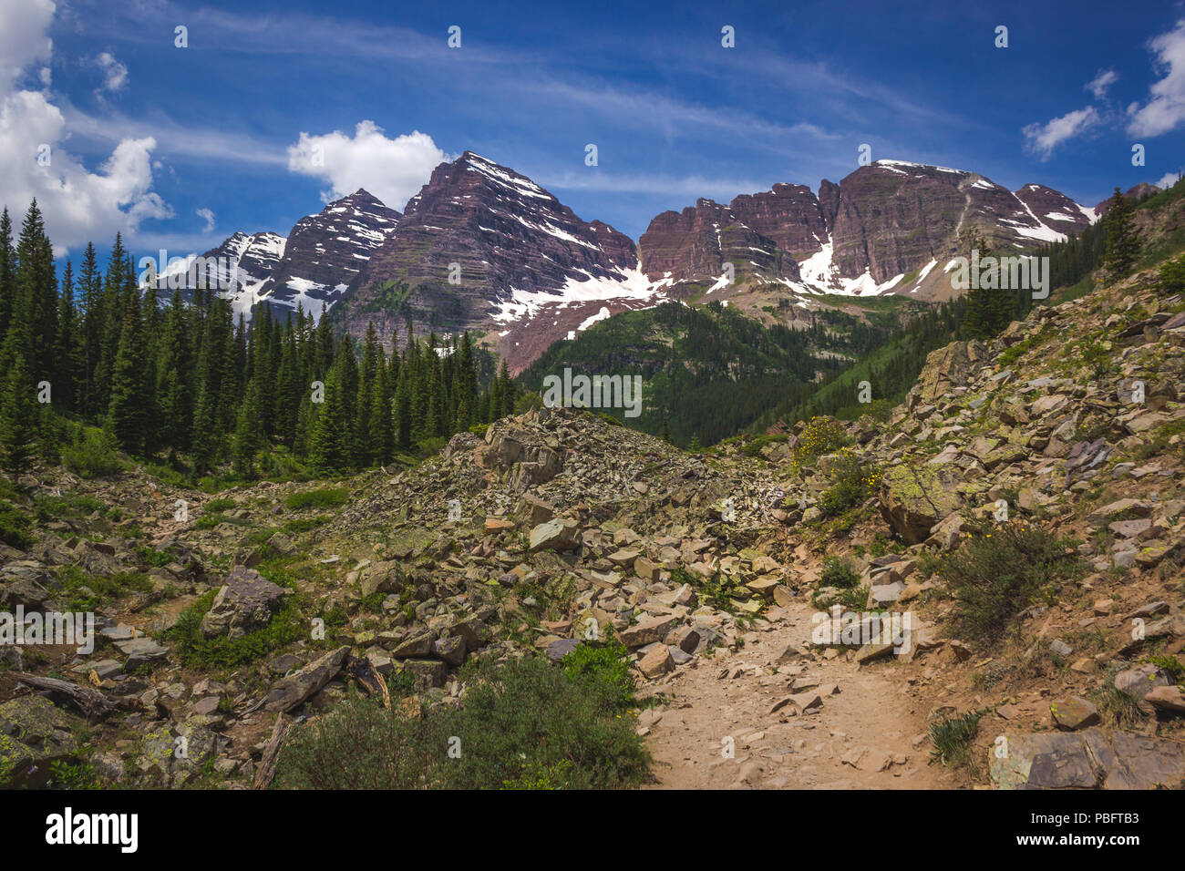 Majestic Maroon Bells Peaks von der rauen Crater Lake Trail gesehen an einem sonnigen Tag mit blauen Himmel im Sommer in der Nähe von Aspen, Colorado Stockfoto