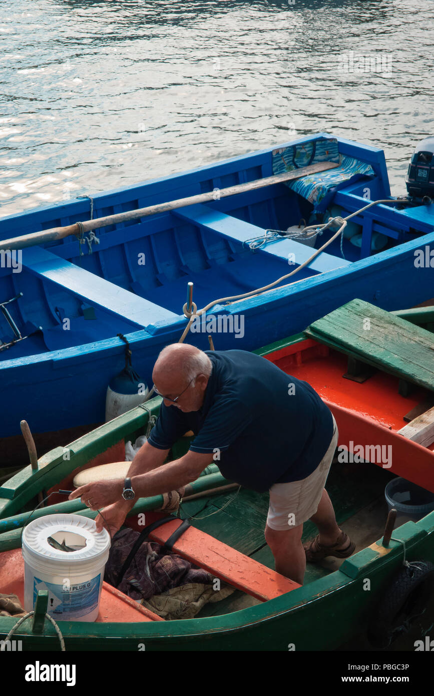 Mola di Bari, Italien, 21.05.2018: Ein Mann eines Nachmittags im Hafen von Mola di Bari auf seinem kleinen Fischerboot, der sich auf den nächsten Ausflug vorbereitet. Stockfoto
