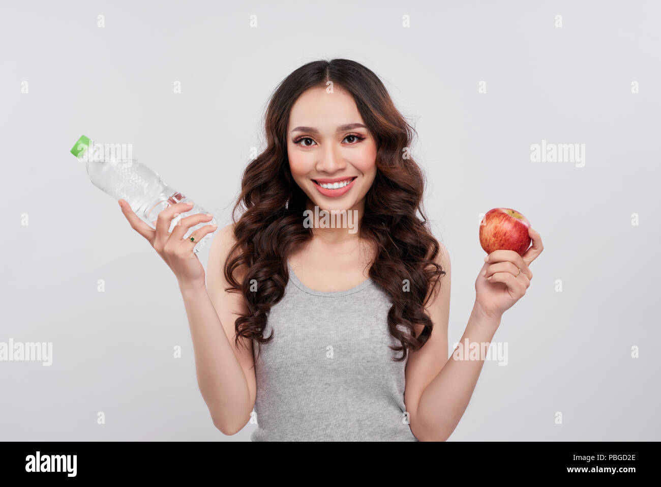 Asiatische Frau mit Smile holding Wasserflasche und Apple auf weißem Hintergrund, gesunde Lebensstile Konzept Stockfoto