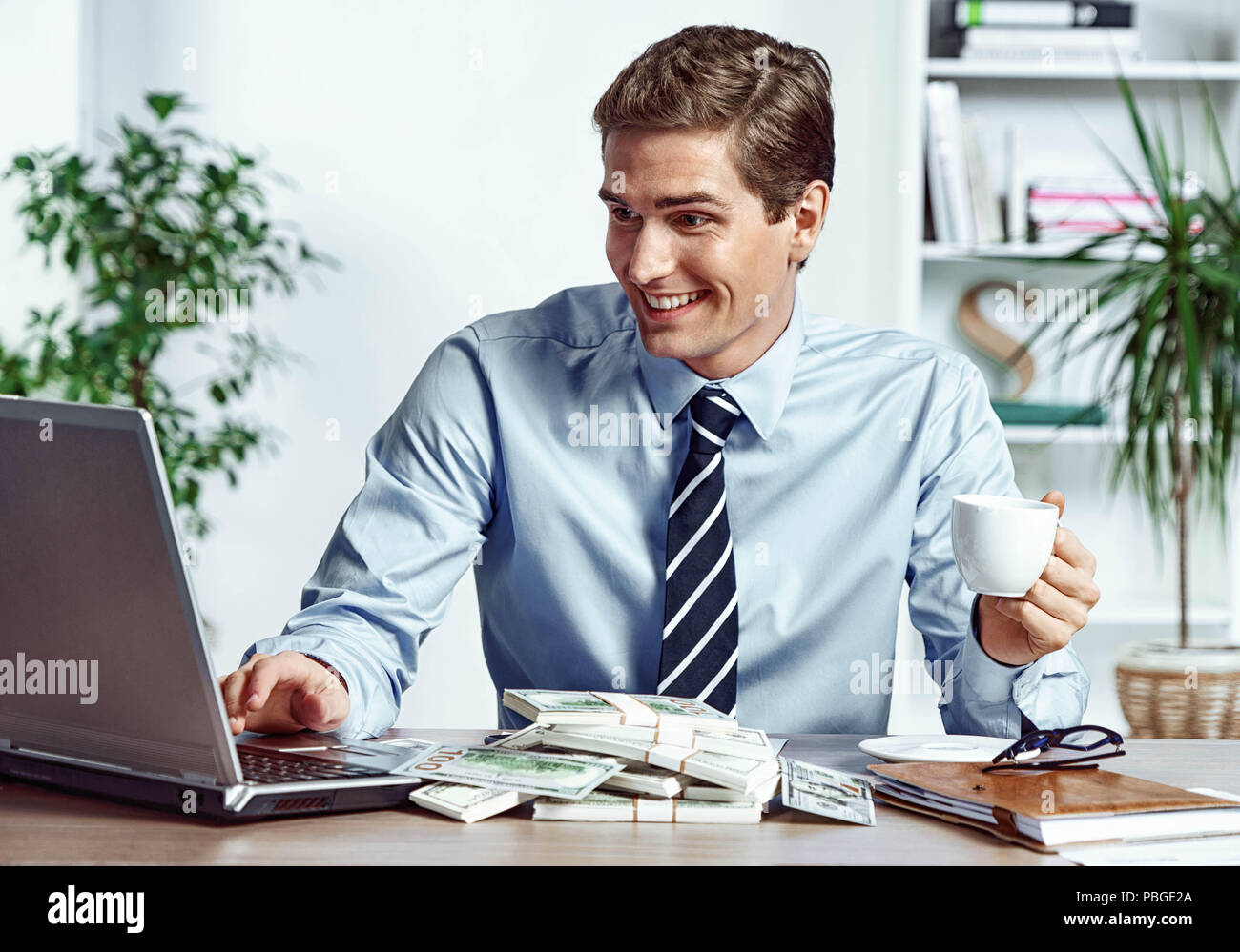 Arbeiter auf dem Laptop und Kaffee zu trinken. Foto der glückliche junge Mann bei der Arbeit im Büro. Business Konzept Stockfoto