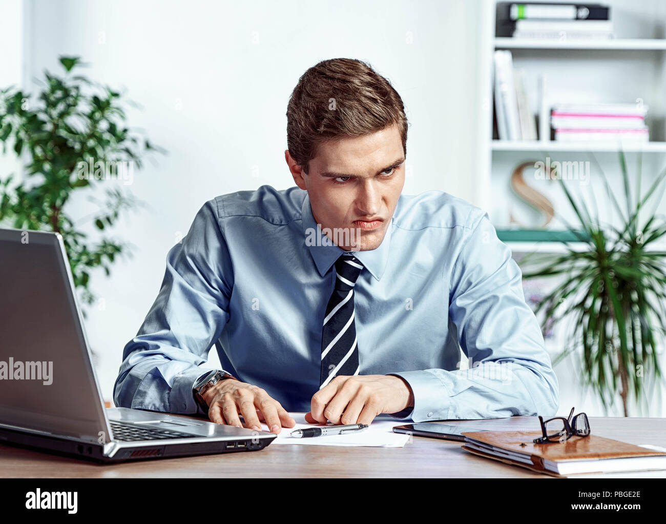 Verärgerte Arbeiter mit unglücklich der Gesichtsausdruck. Foto junger Mann bei der Arbeit im Büro. Business Konzept Stockfoto