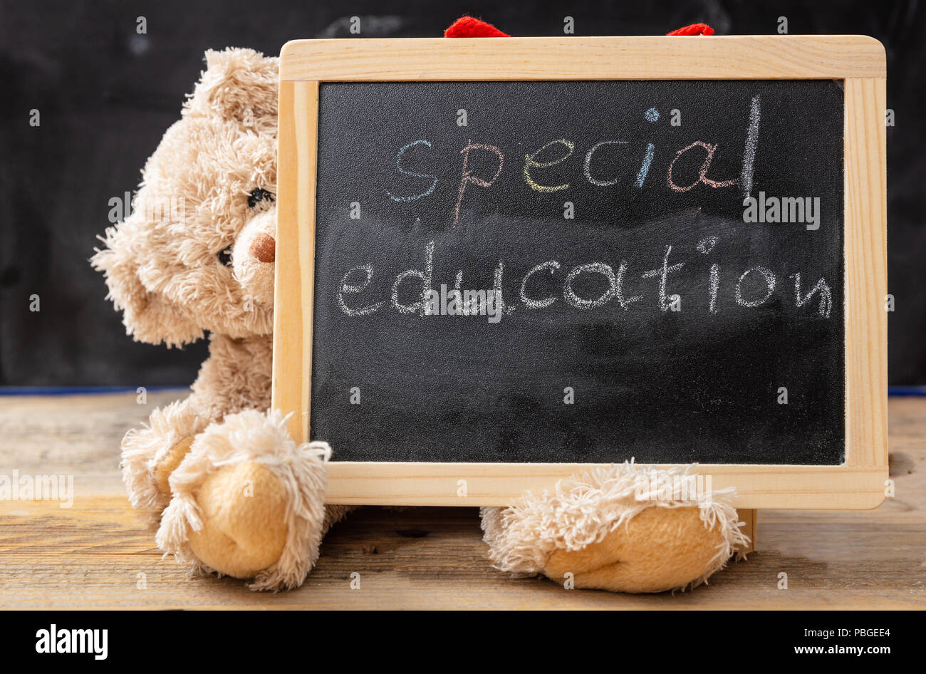 Spezielle Ausbildung. Teddybär hinter einer Tafel versteckt. Special Education text Zeichnung an der Tafel Stockfoto