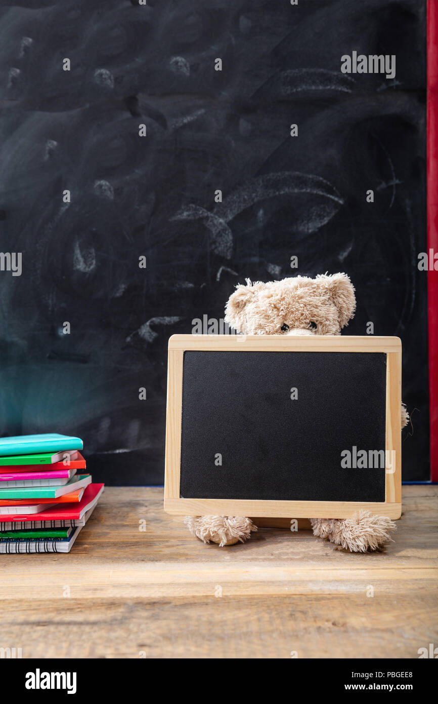 Zurück zu Schule. Teddybär und leere Tafel mit Rahmen auf hölzernen Schreibtisch, Platz für Text Stockfoto