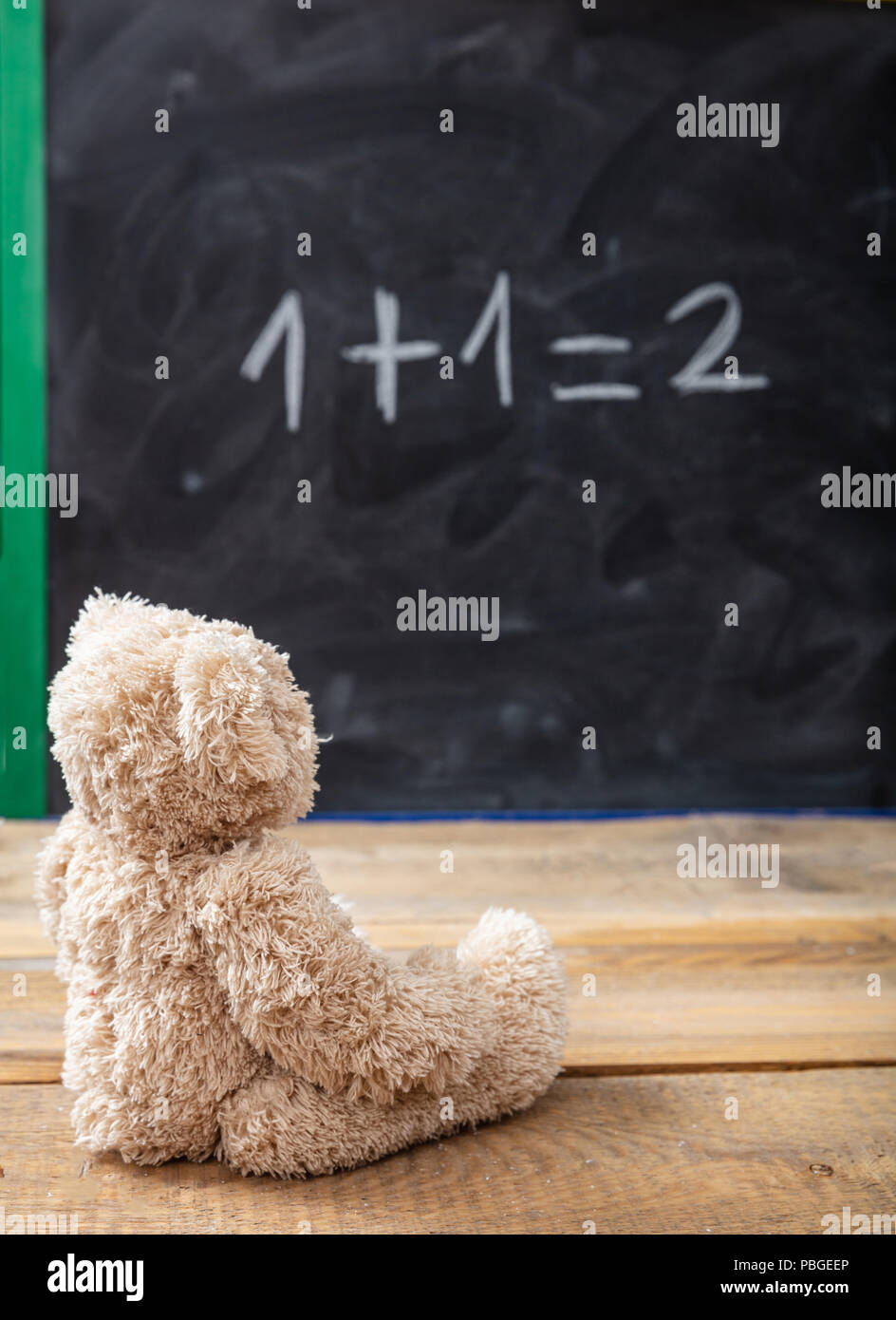 Schule Klasse Math. Teddy Bär auf eine einfache Gleichung auf einer Tafel. Eins plus Eins gleich zwei Stockfoto
