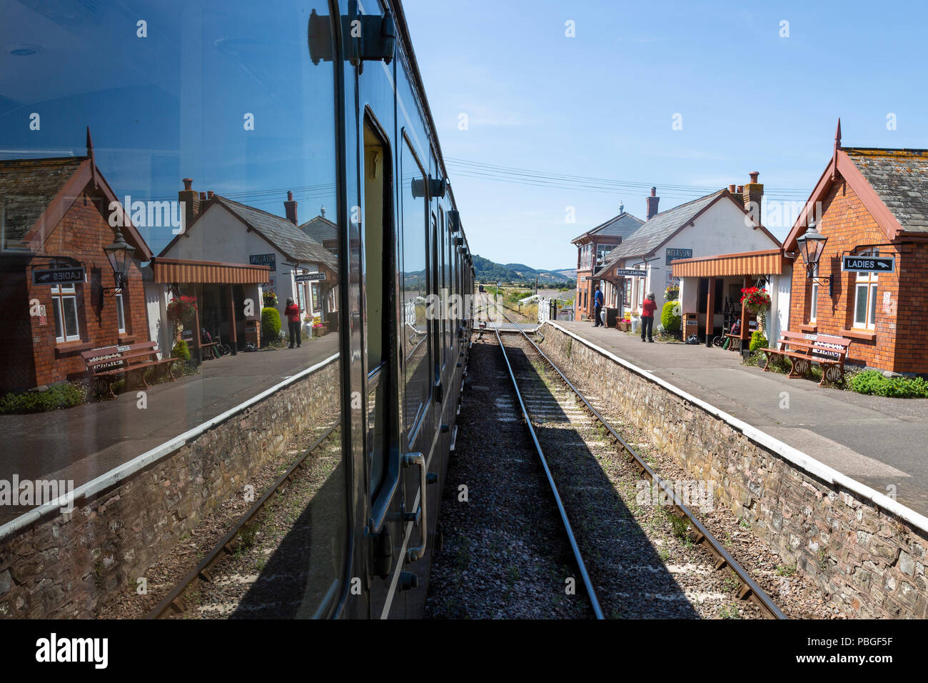 Blue Anchor Station, auf der West Somerset Railway, und ihre Reflexion in der Seite einer Beförderung auf der Schiene. Stockfoto