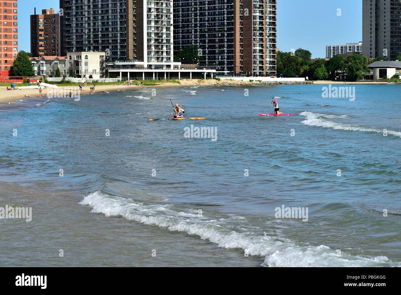 Chicago, Illinois, USA. Paar ihren Weg an Land und an Bord up Paddle Boards auf Hollywood Beach stehen, auch als Kathy Osterman Beach bekannt. Stockfoto