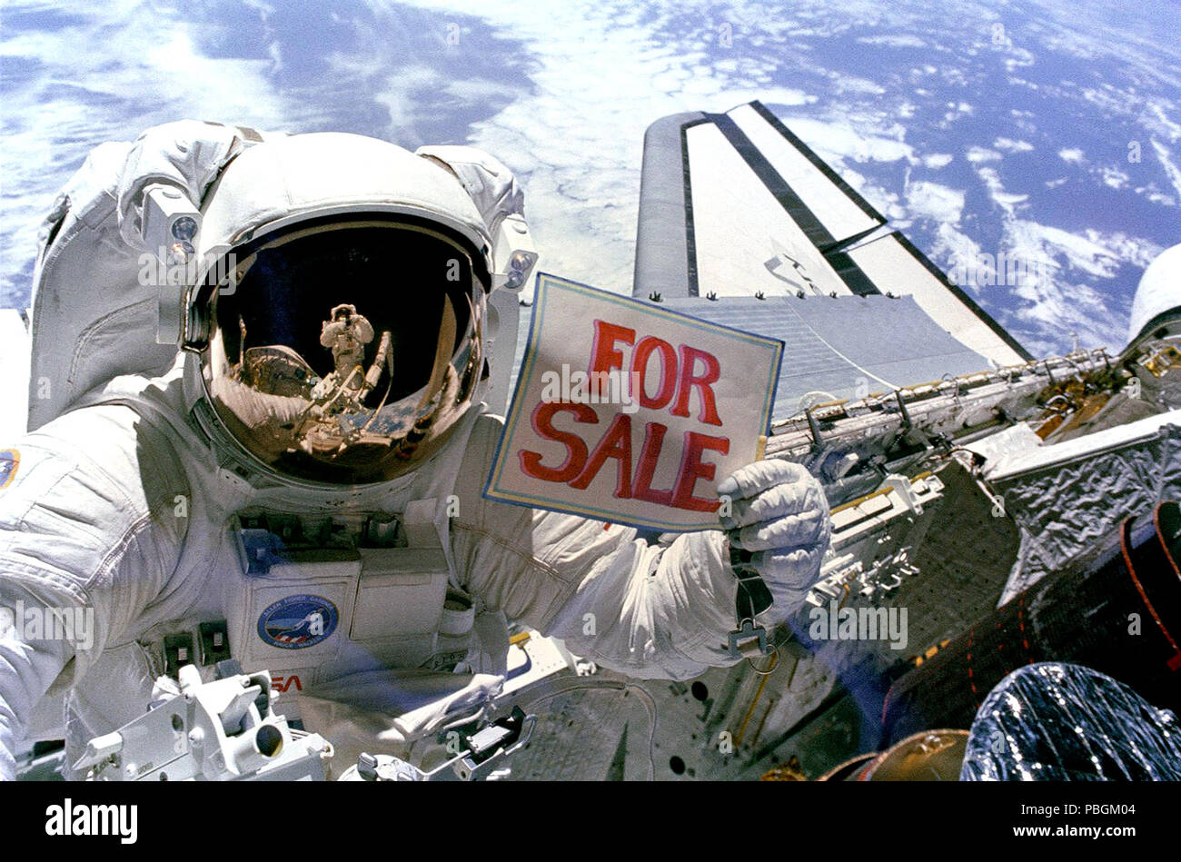 Astronaut Dale A. Gardner, der gerade den größten Teil seines zweiten Extra Vehicular Activity (EVA) Zeitraum in drei Tagen, hält ein Schild "Zum Verkauf" bezieht sich auf die beiden Satelliten, Stockfoto
