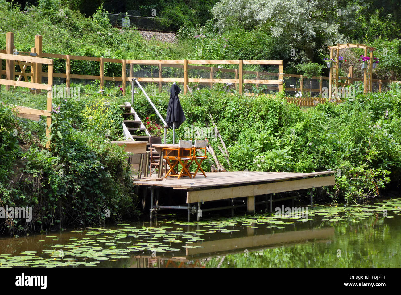 Tische und Stühle auf einer eigenen Bootsanleger am Ende der Garten am Fluss, Medway, Kent, England Stockfoto
