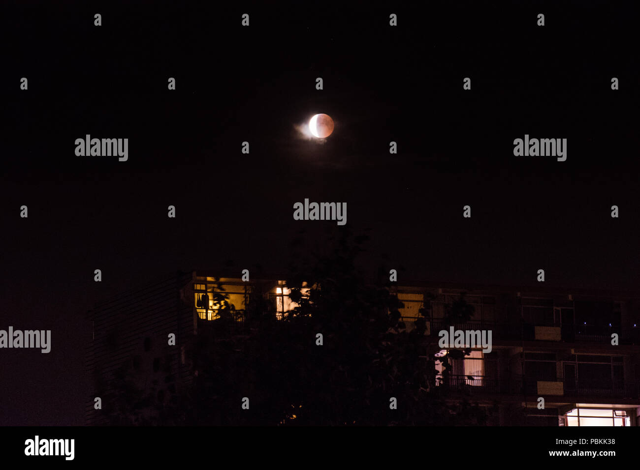 Amsterdam, Niederlande - 07-27-2018 Dunkle Mondfinsternis Nacht und beleuchteten Balkon Windows. Mond führt hinter der Erde und in den Schatten. Stockfoto