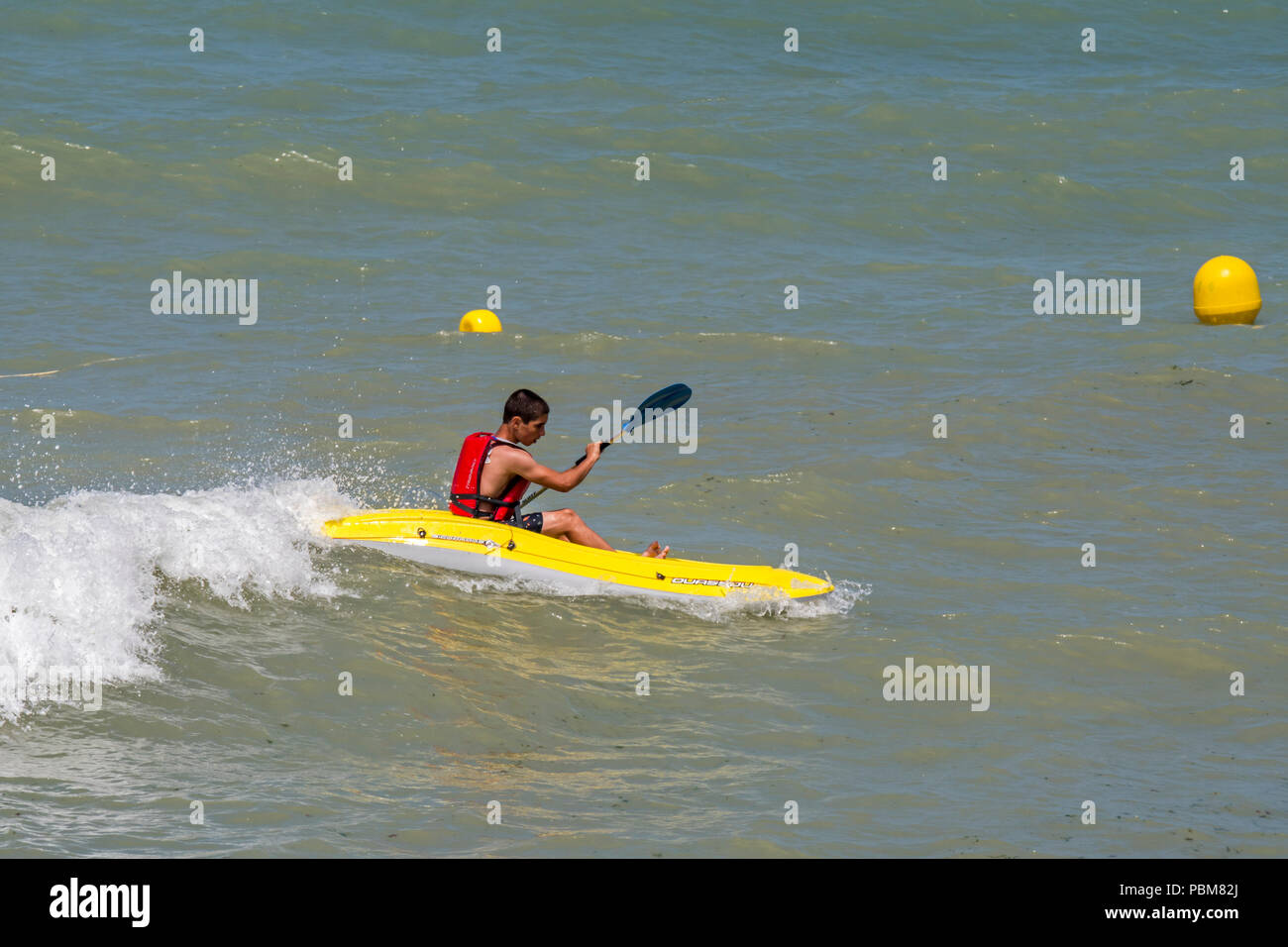 Sportliche Teenager tragen Rettungsweste/Schwimmweste Fahrten wave im Kajak auf dem Meer im Sommer Stockfoto