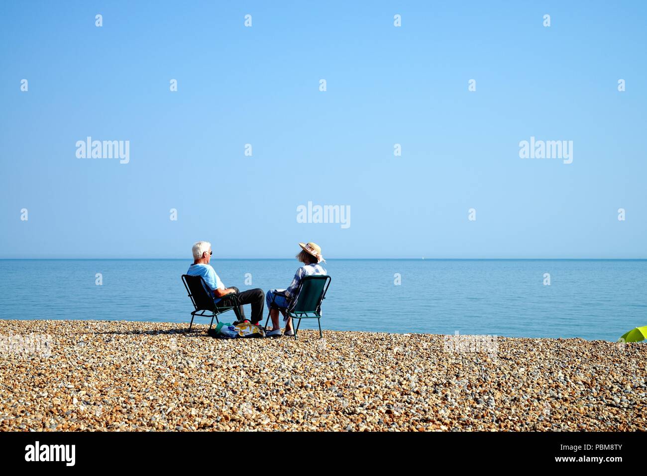 Ältere weiß Paar am Strand von Hastings an einem heissen Sommertag, East Sussex England Großbritannien Stockfoto