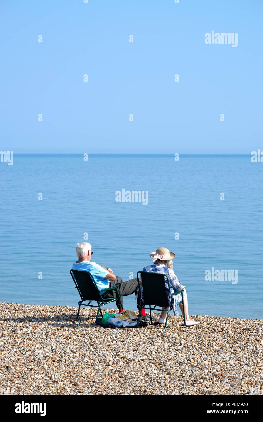 Ältere weiß Paar am Strand von Hastings an einem heissen Sommertag, East Sussex England Großbritannien Stockfoto