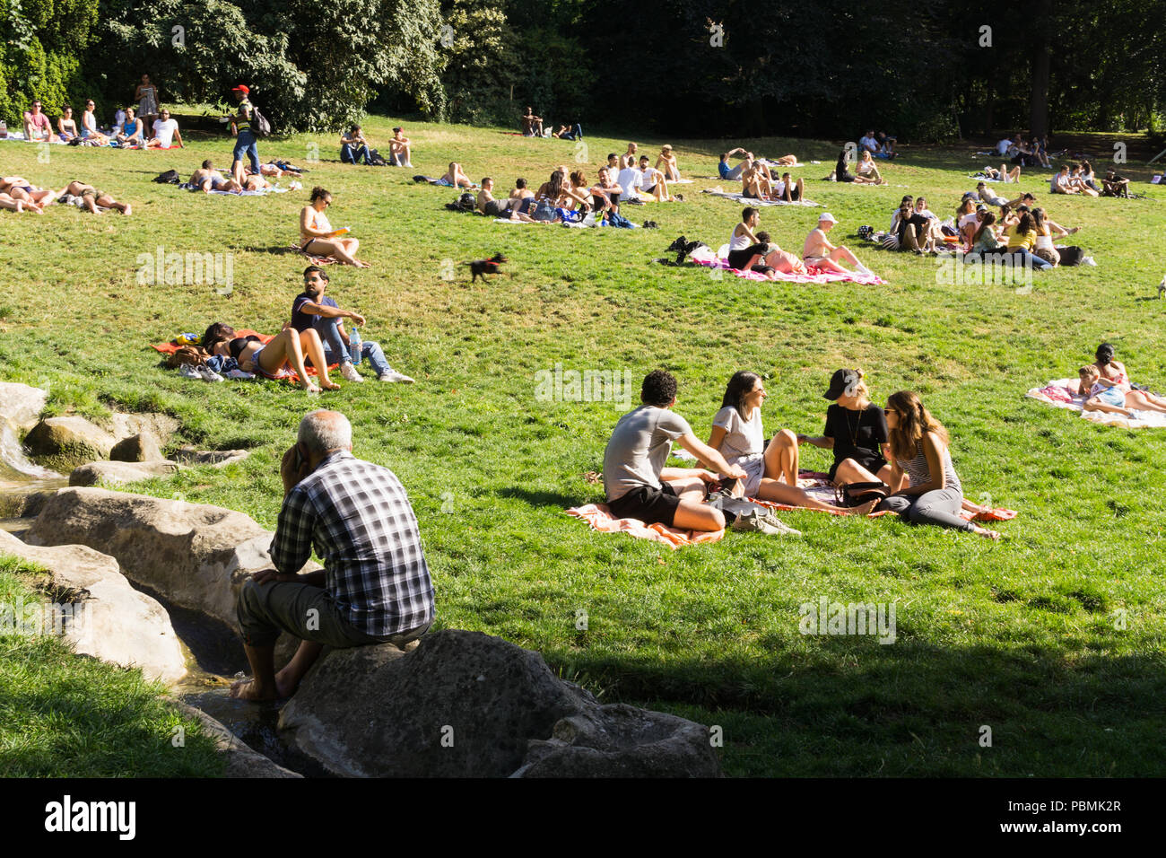 Paris Park - Leute genießen heißen Nachmittag im Parc des Buttes Chaumont in Paris, Frankreich, Europa. Stockfoto
