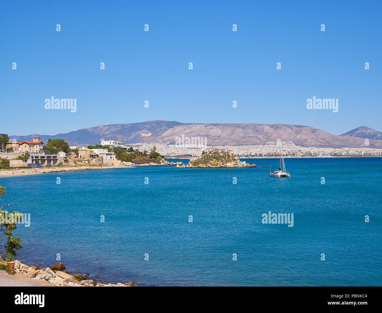 Mikrolimano Bucht und Stalis oder Nisos Koumoudourou Insel mit Palacio Faliro im Hintergrund. Region Attika, Griechenland. Stockfoto