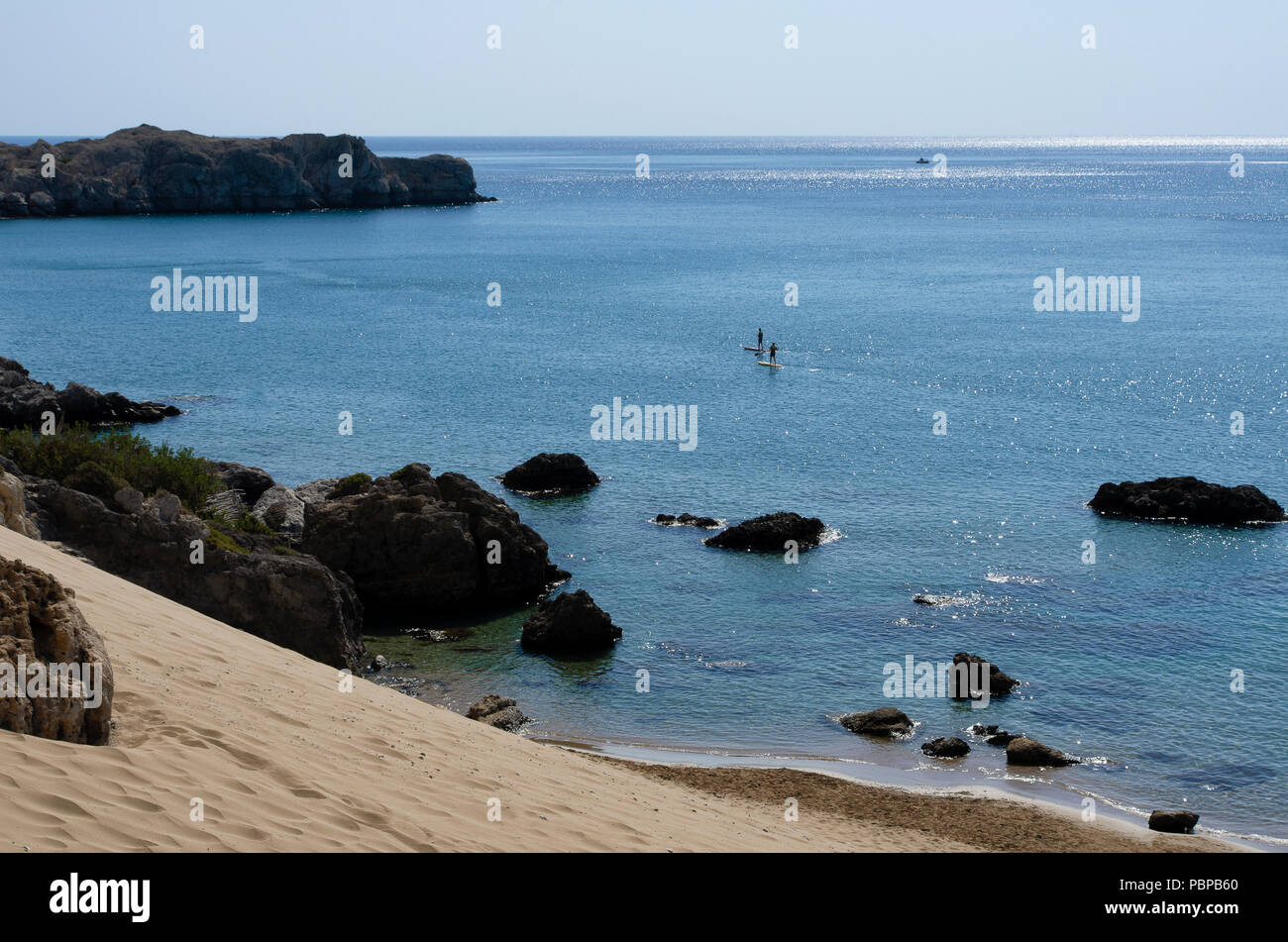 Mittelmeerküste mit blauem Meer und zwei nicht identifizierte Touristen im Abstand eingerückt standup paddleboarding Stockfoto
