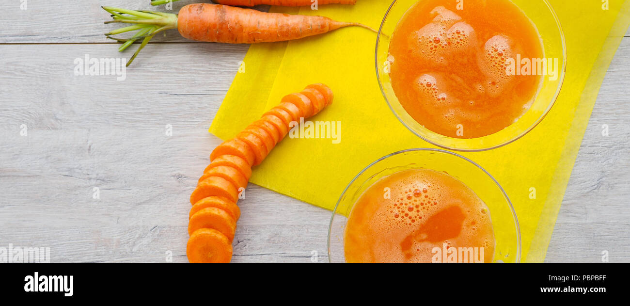 Gläser Karottensaft und frische Karotten auf Holzbrett Stockfoto