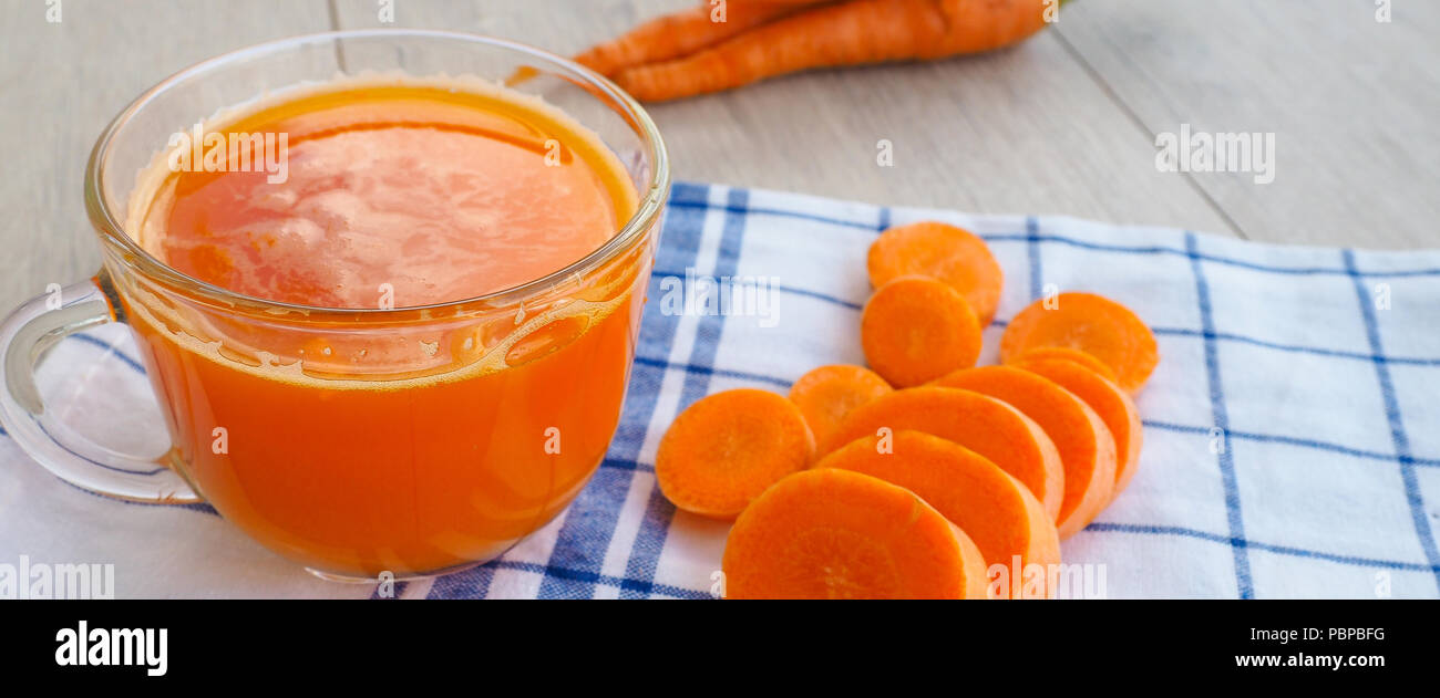 Gläser Karottensaft und frische Karotten auf Holzbrett Stockfoto