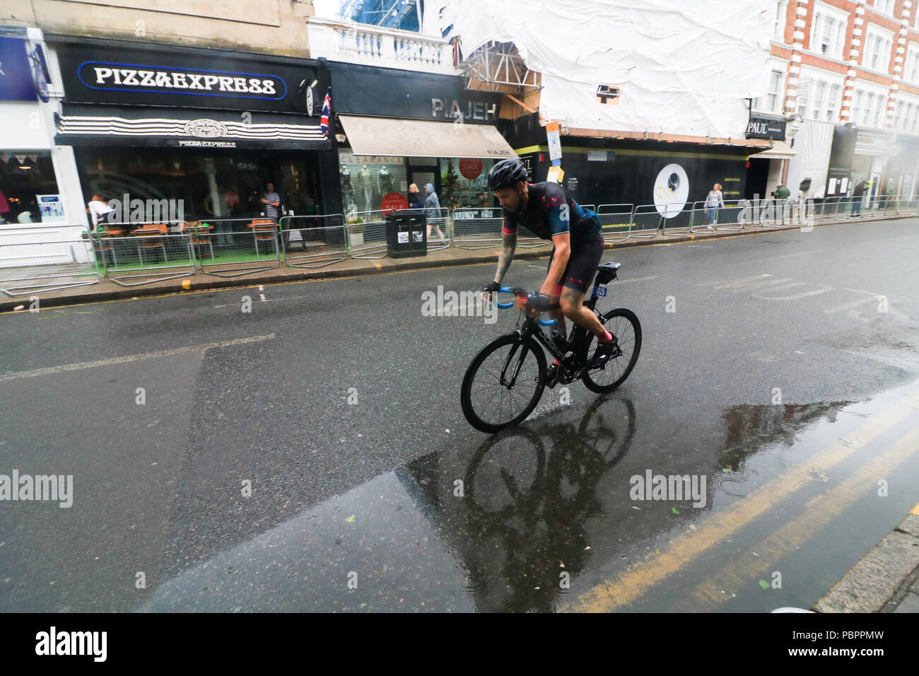 London, Großbritannien. 29. Juli 2018. Radfahrer durch Wimbledon Village in der aufsichtsrechtlichen London Surrey 100 Classic Event in nassen Bedingungen wie die Regenzeit, unten zu kommen. Die aufsichtsrechtlichen Fahrt London-Surrey 100 in seiner sechsten Jahr feiert das Vermächtnis für die London 2012 die Olympischen und Paralympischen Spiele erstellt Radfahren und folgt einer 100km Route auf geschlossenen Straßen durch das Kapital und in die Landschaft von Surrey Credit: Amer ghazzal/Alamy leben Nachrichten Stockfoto