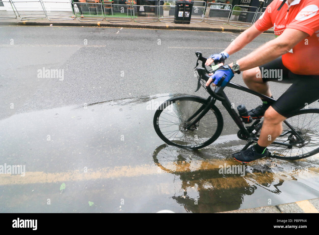 London, Großbritannien. 29. Juli 2018. Radfahrer durch Wimbledon Village in der aufsichtsrechtlichen London Surrey 100 Classic Event in nassen Bedingungen wie die Regenzeit, unten zu kommen. Die aufsichtsrechtlichen Fahrt London-Surrey 100 in seiner sechsten Jahr feiert das Vermächtnis für die London 2012 die Olympischen und Paralympischen Spiele erstellt Radfahren und folgt einer 100km Route auf geschlossenen Straßen durch das Kapital und in die Landschaft von Surrey Credit: Amer ghazzal/Alamy leben Nachrichten Stockfoto