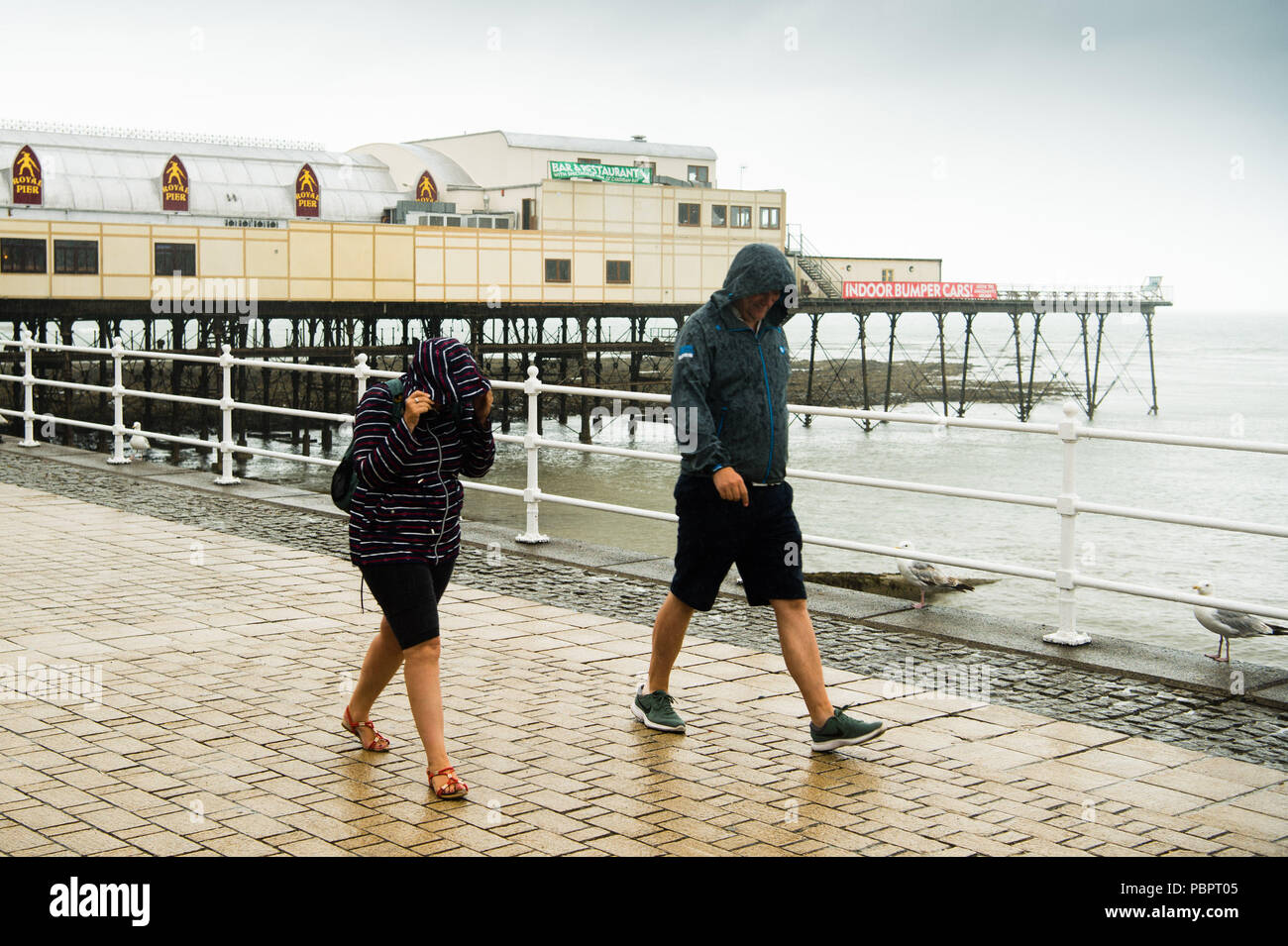 Aberystwyth Wales UK, Sonntag, den 29. Juli 2018 UK Wetter: Leute auf einem grauen, nassen und bedeckt Sonntag getränkt am Meer in Aberystwyth auf der West Wales Küste. Die langen Hitzewelle bricht schließlich unten mit Gewitter und sintflutartige Regenfälle über viel des Landes Foto: Keith Morris/Alamy leben Nachrichten Stockfoto