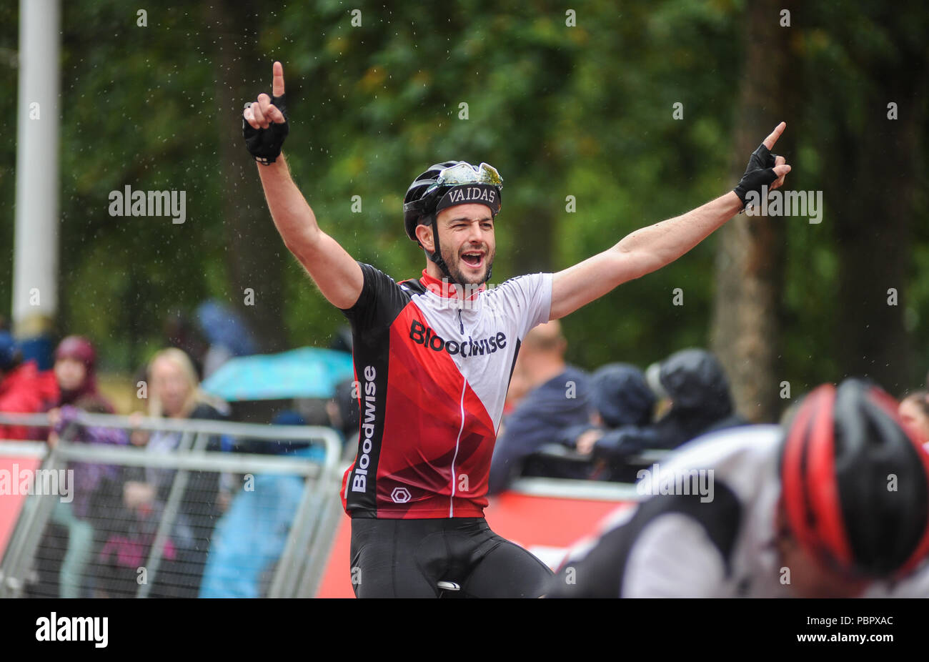 London, UK, 29. Juli 2018. Prudential Fahrt London-Surrey 100. Reiter feiern Überqueren der Ziellinie auf der Mall im Regen am Ende der London - Surrey 100, die sieht 26.000 amateur Radfahrer auf eine Cycling Challenge wie kein anderer durch London und Surrey Nehmen auf einer ähnlichen Route wie die 2012 in London olympische Straßenrennen, als Teil des aufsichtsrechtlichen RideLondon Festival der Radfahren Wochenende. @ David Rebhuhn/Alamy leben Nachrichten Stockfoto