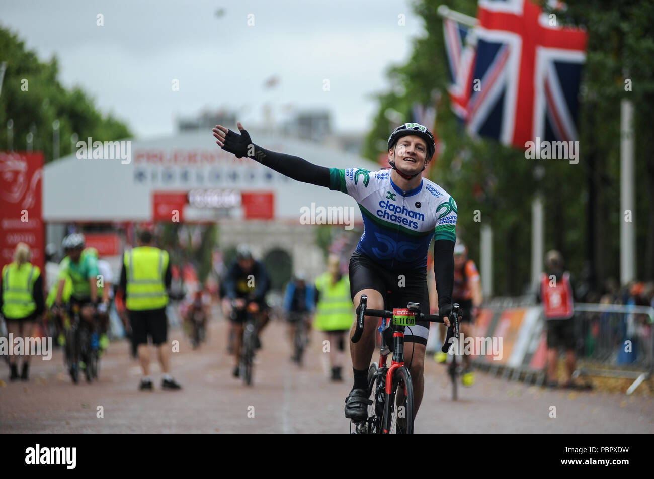 London, UK, 29. Juli 2018. Prudential Fahrt London-Surrey 100. Reiter feiern Überqueren der Ziellinie auf der Mall im Regen am Ende der London - Surrey 100, die sieht 26.000 amateur Radfahrer auf eine Cycling Challenge wie kein anderer durch London und Surrey Nehmen auf einer ähnlichen Route wie die 2012 in London olympische Straßenrennen, als Teil des aufsichtsrechtlichen RideLondon Festival der Radfahren Wochenende. @ David Rebhuhn/Alamy leben Nachrichten Stockfoto