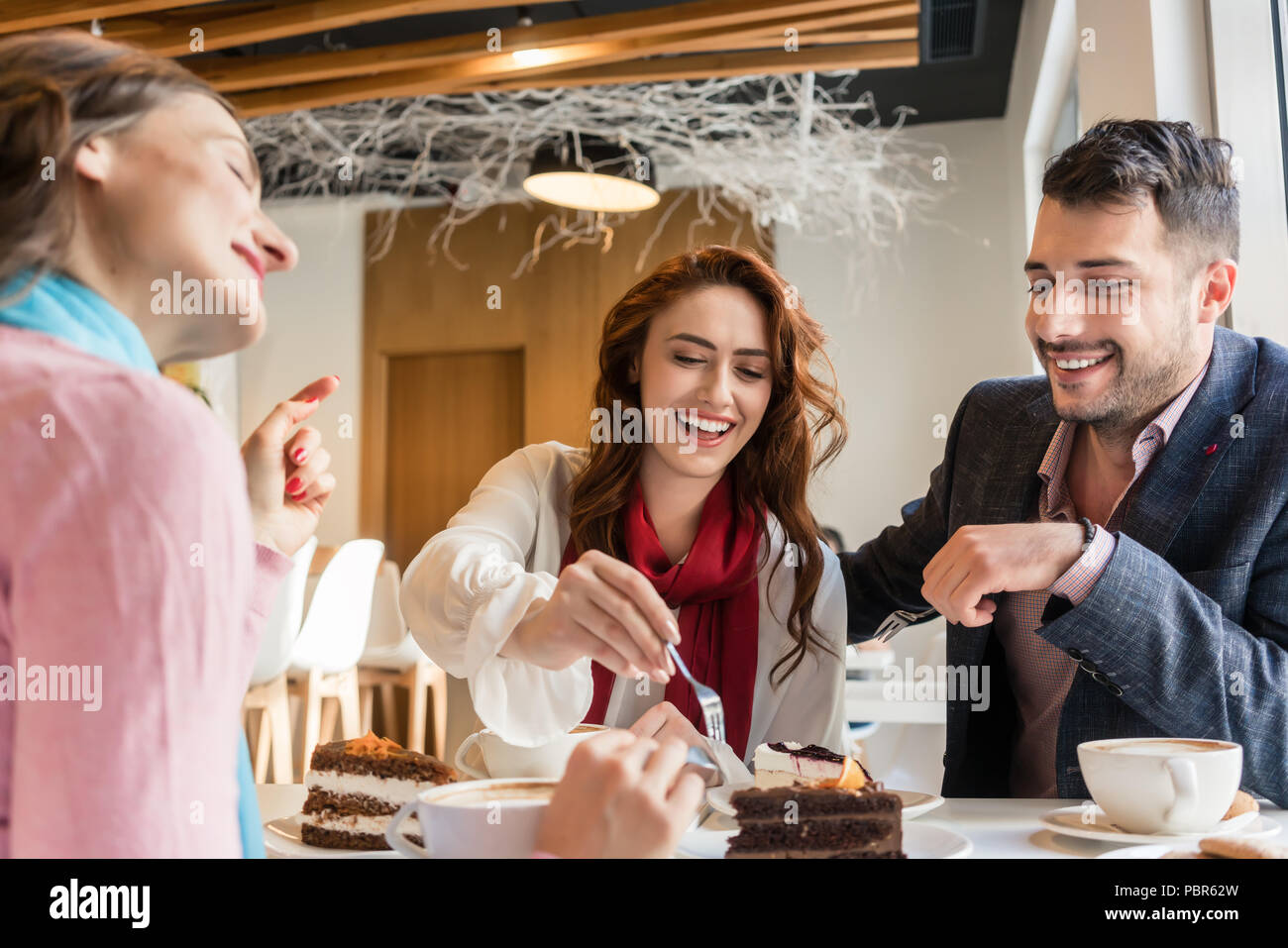 Drei Freunde lächelnd beim Essen des leckeren Kuchen in Ihrer cheat Tag Stockfoto