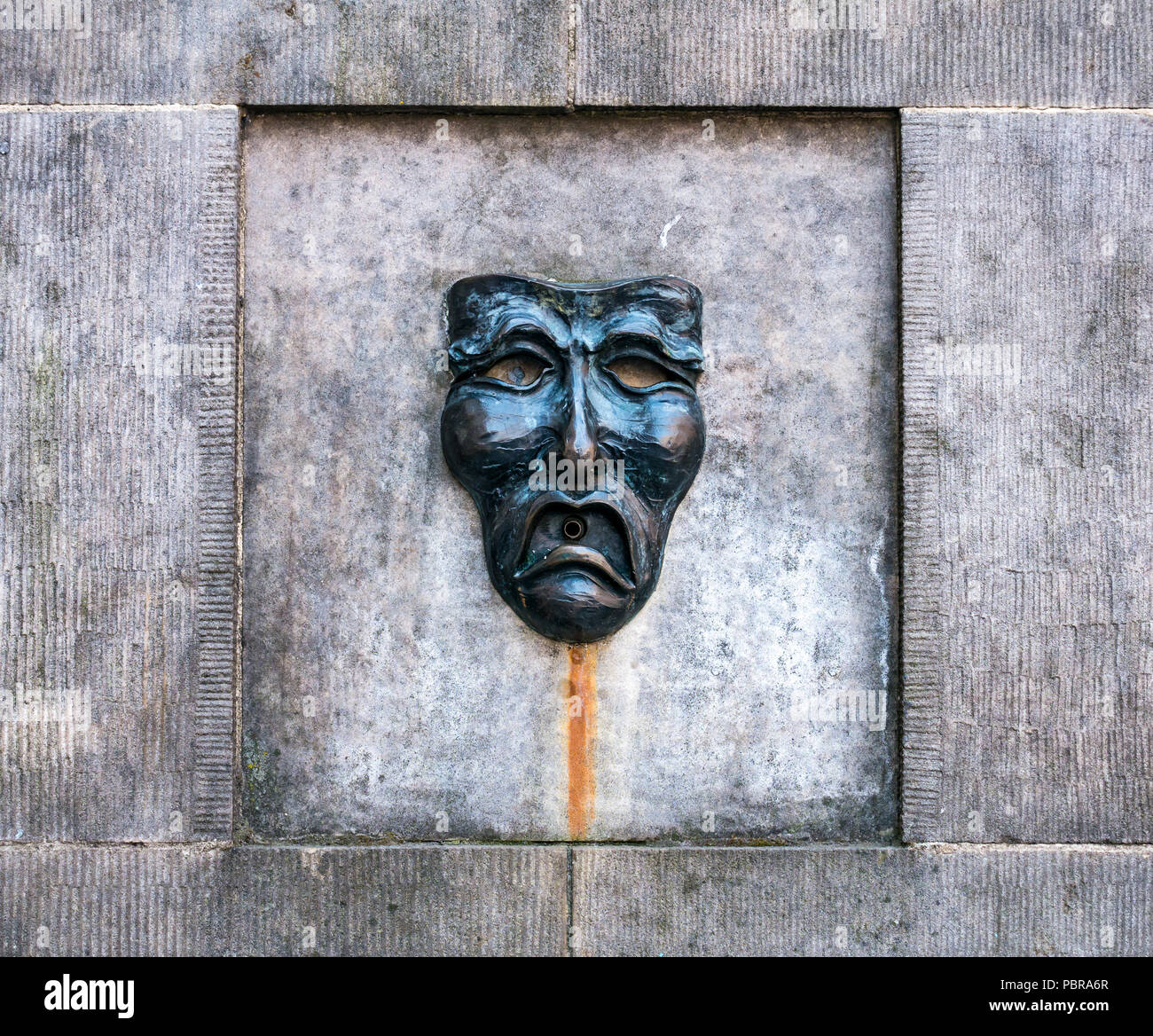 Nahaufnahme von Fringe symbol Komödie die Maske des traurigen Gesicht auf Gut Kopf Street Fountain außerhalb Fringe Box Office, Royal Mile, Edinburgh, Schottland, Großbritannien Stockfoto