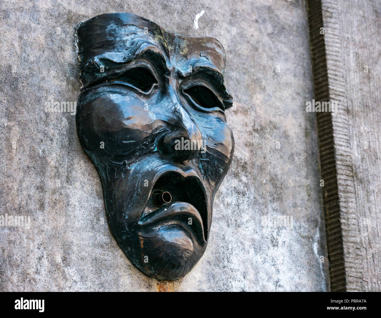 Nahaufnahme von Fringe symbol Komödie die Maske des traurigen Gesicht auf Gut Kopf Street Fountain außerhalb Fringe Box Office, Royal Mile, Edinburgh, Schottland, Großbritannien Stockfoto