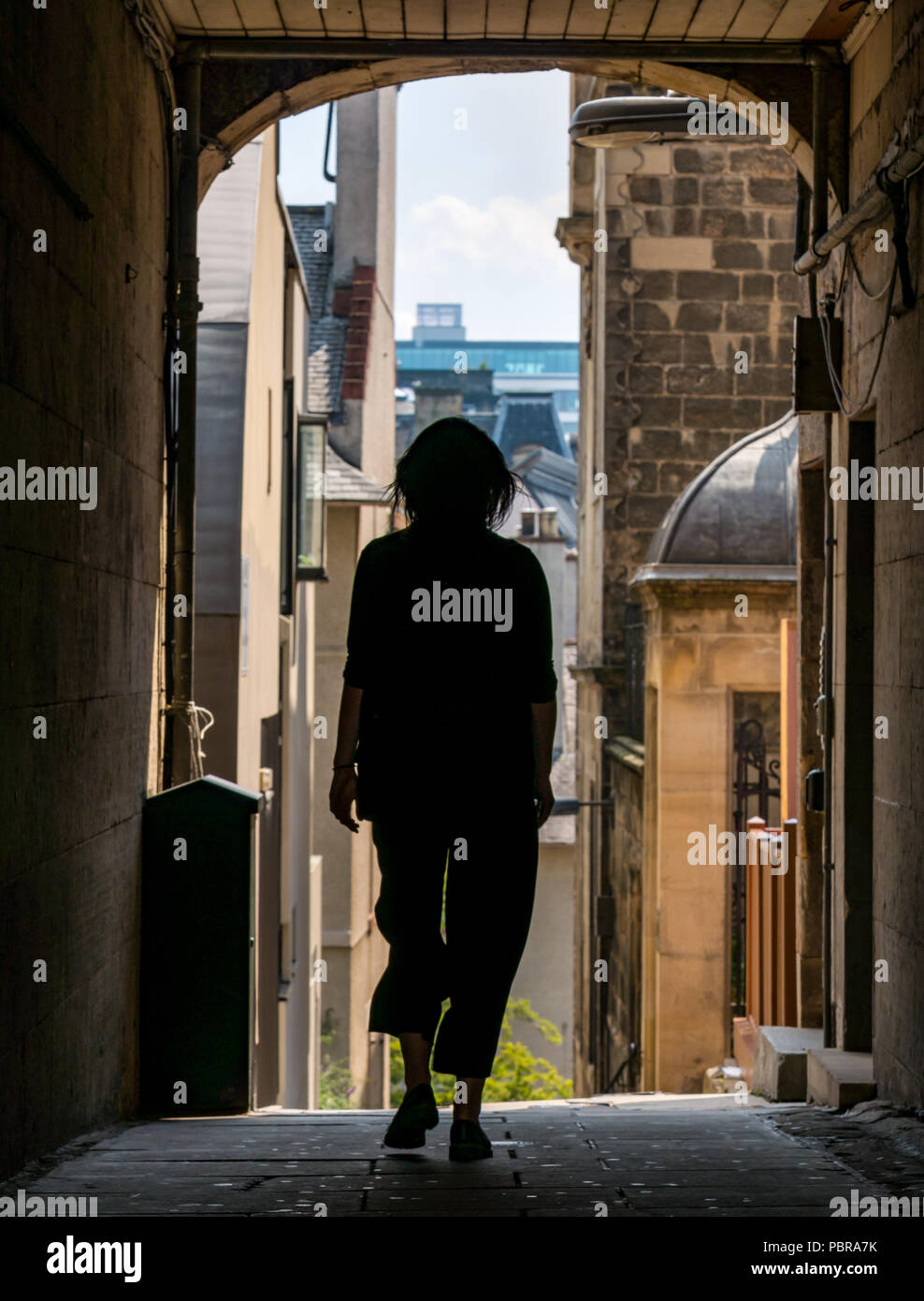 Silhouette einer Frau zu Fuß durch alte Baugruppe schließen, die Royal Mile, Edinburgh, Schottland, Großbritannien im Sommer Stockfoto