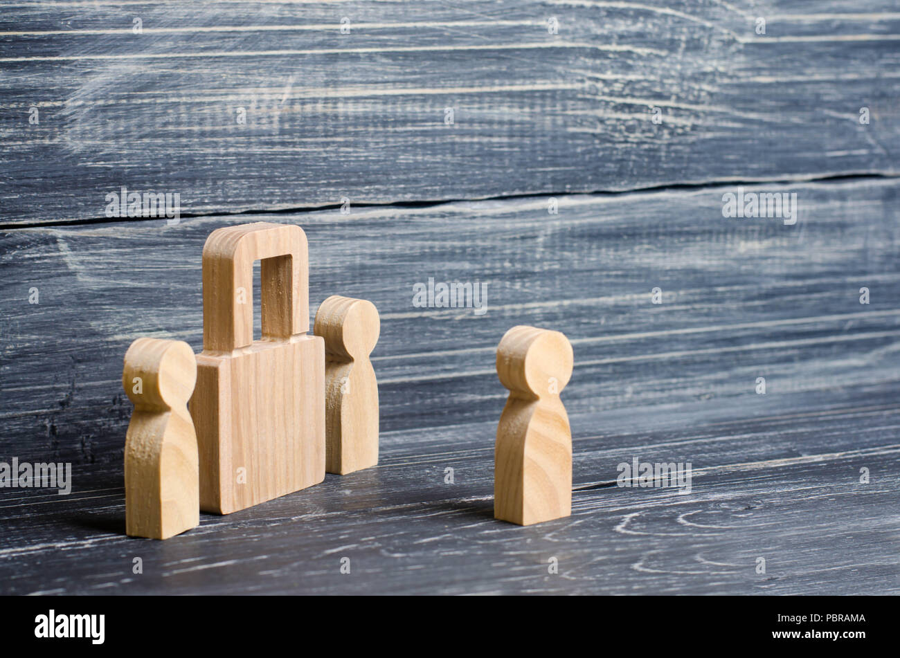 Zwei Menschen stehen in der Nähe ein Vorhängeschloss und halten Geheimnisse, Informationen, Eingang. Hölzerne Figuren von Personen wachen böse Spione. Das Konzept der Stockfoto