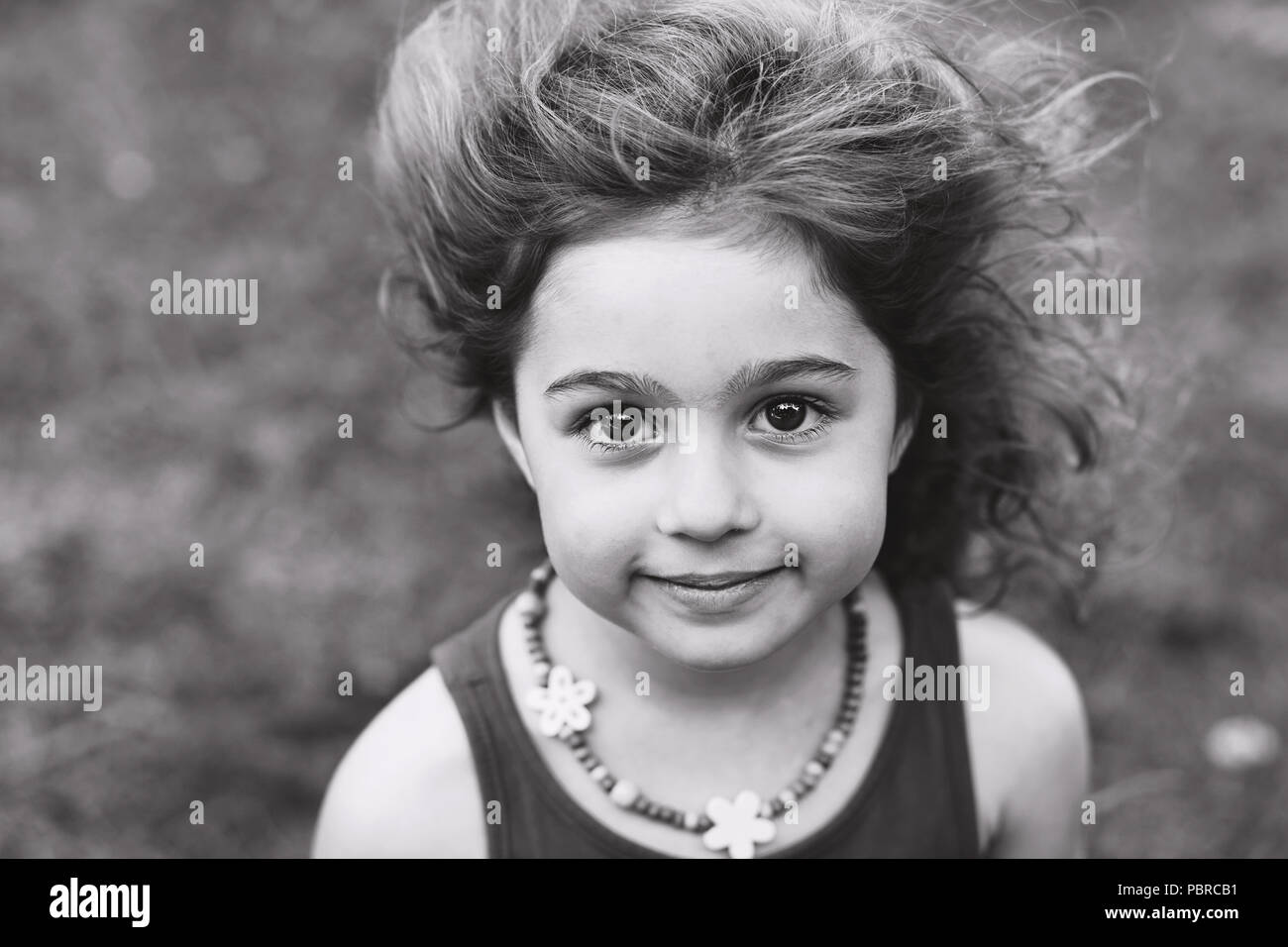 Schwarz-weiß-Porträt von niedlichen kleinen Mädchen lächelnd außerhalb Stockfoto